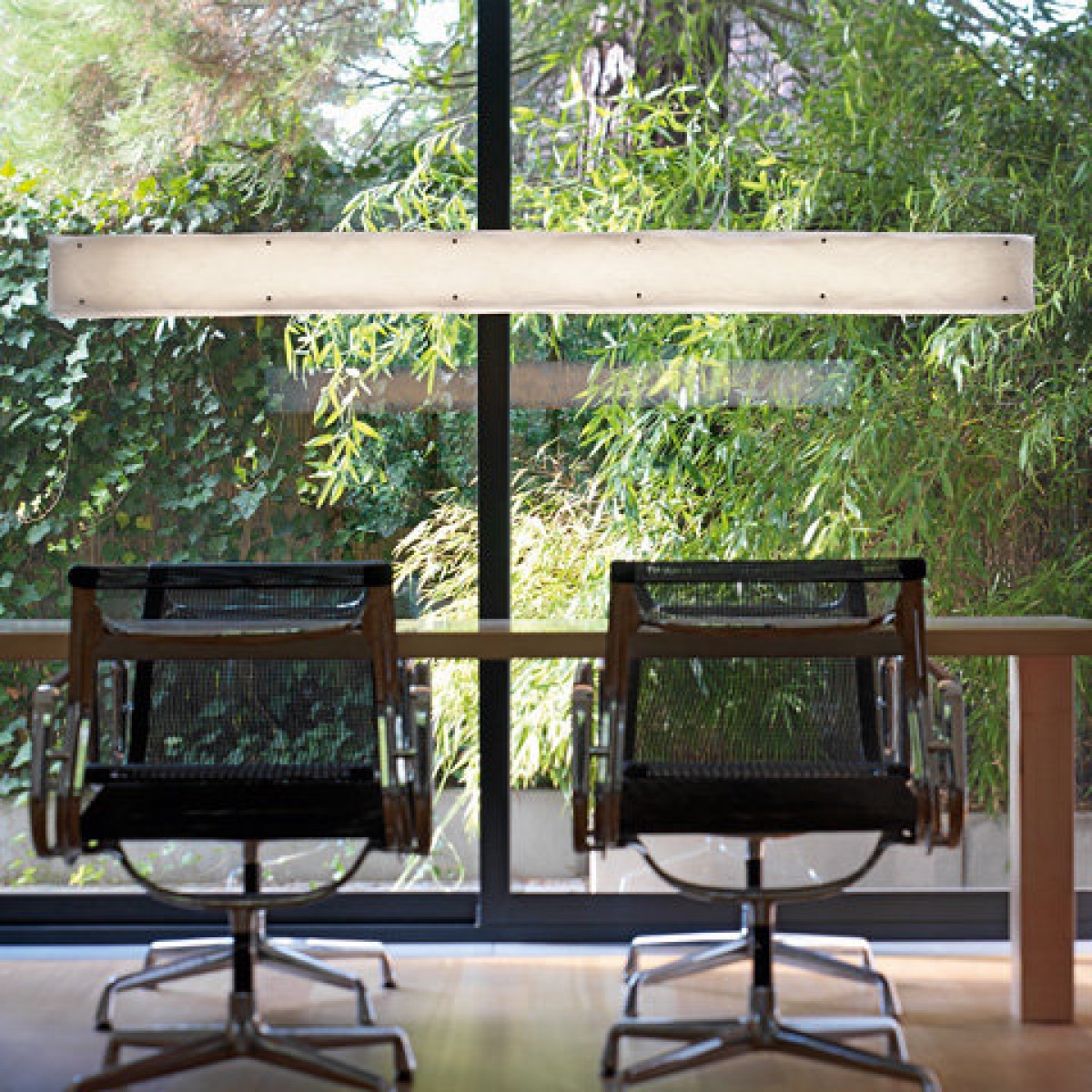 One by One Pendelleuchte von Belux, längliche Deckenleuchte über einem Tisch mit Stühlen.