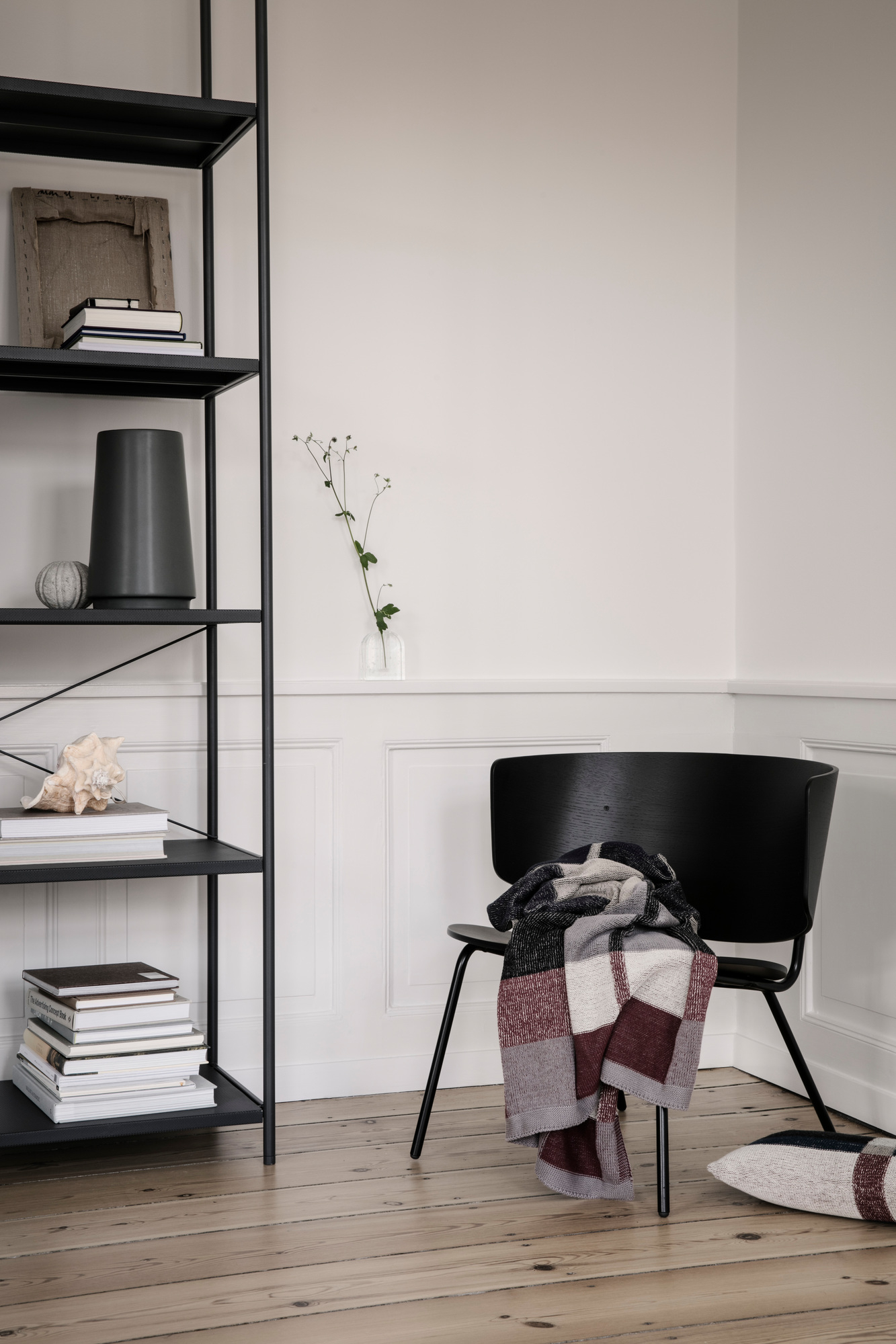 Schwarzes Punctual Shelving System 1x5 von Ferm Living mit Deko-Objekten und einem Stuhl im Raum.