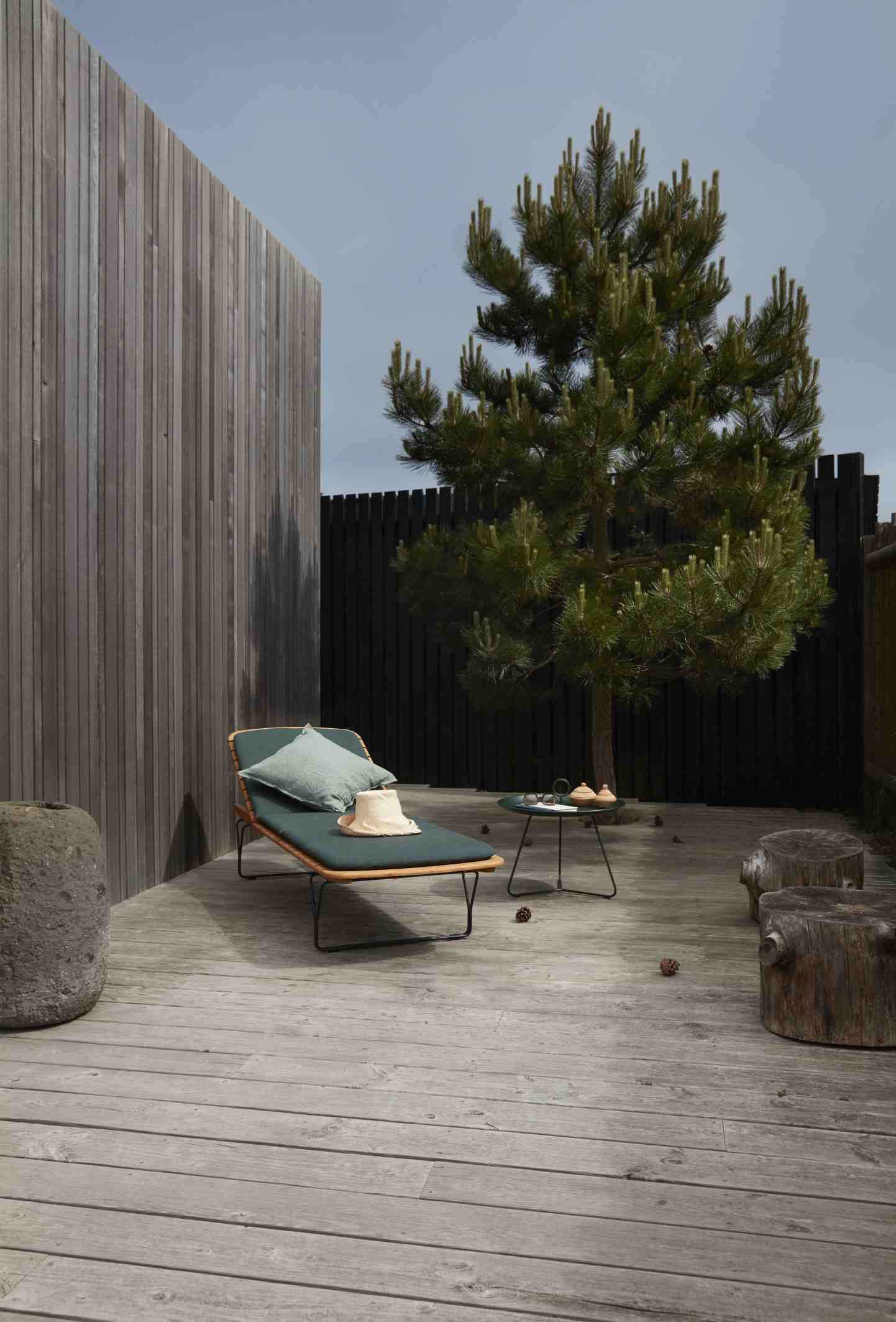 Molo Outdoor Cushion Kissen auf Houe Sonnenliege im Garten mit Beistelltisch und Dekoration.