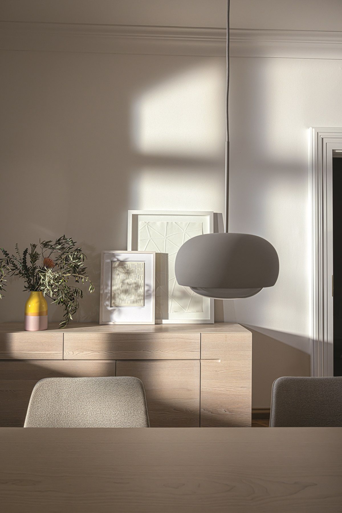 Detailaufnahme vom E8 Tisch / Esstisch Massivholz mit Lampe, Sideboard und Stühlen im modernen Esszimmer.