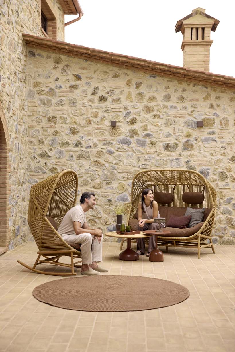 Mann und Frau entspannen auf Cane-Line Gartenmöbeln: Hive Sofa und Sessel aus Rattan.