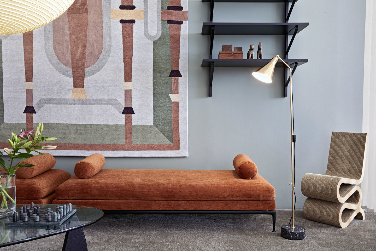 Innenaufnahme eines Wohnzimmers mit Vitra Wiggle Side Chair Stuhl aus Pappe neben einer Liege.