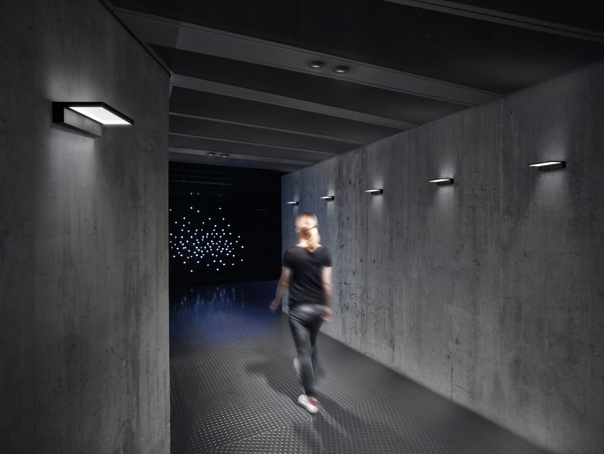 Chromfarbene Crib Wall Wandleuchte von Serien Lighting an einer Betonwand in einem Flur.