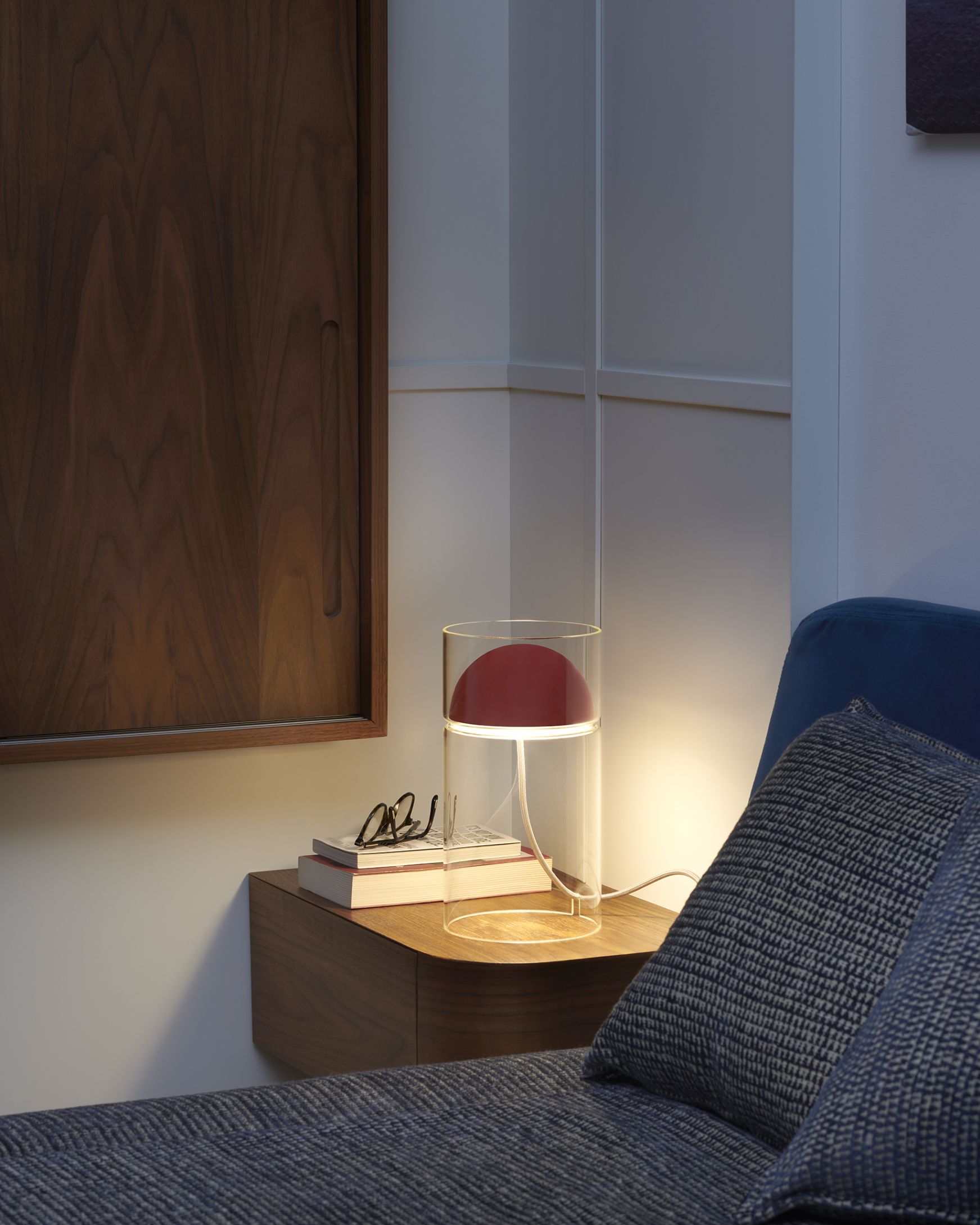 Medusa Tischleuchte von Oluce: Moderne Lampe mit rotem Schirm und Glaszylinder auf Nachttisch.