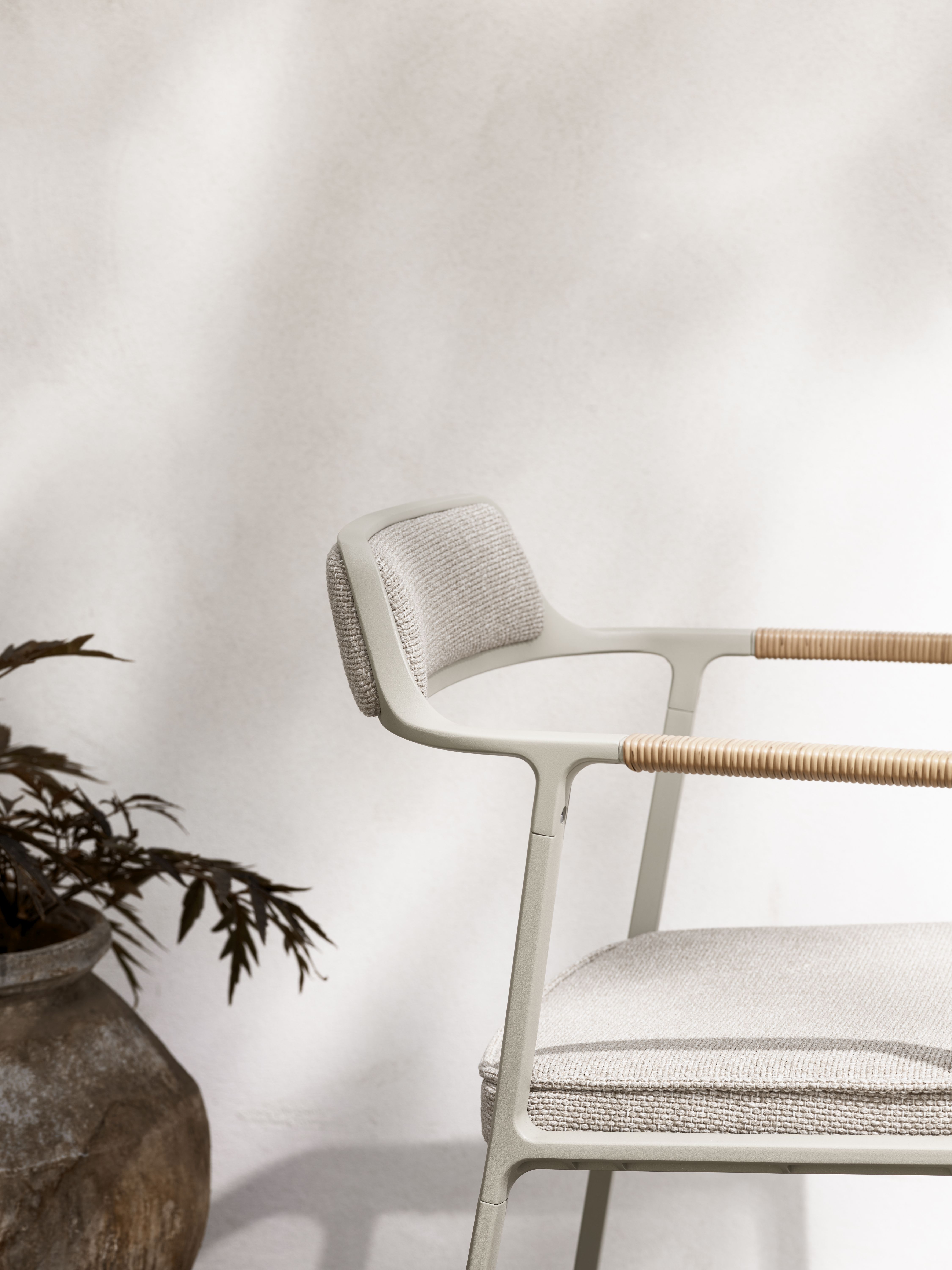 Detailaufnahme des Vipp Open-Air Outdoor Stuhls mit hellgrauem Bezug und Rattan-Armlehnen. Gartenmöbel für Terrasse.
