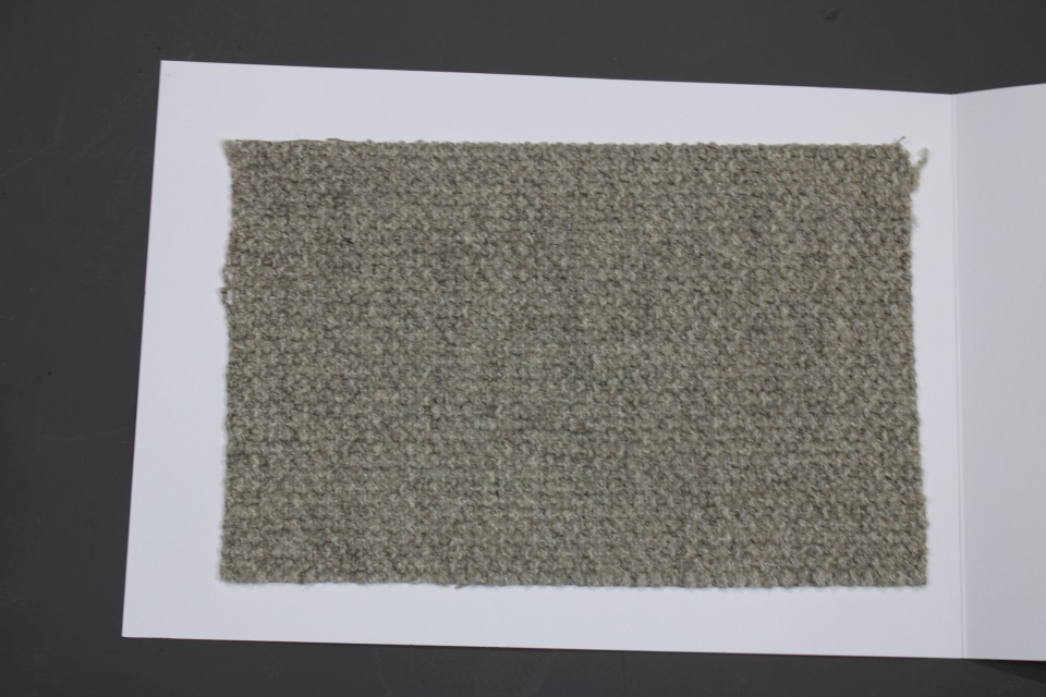 Stoffmusterkarte Cor Gruppe 82: Nahaufnahme eines grauen, melierten Möbelstoff-Musters auf weißem Karton.