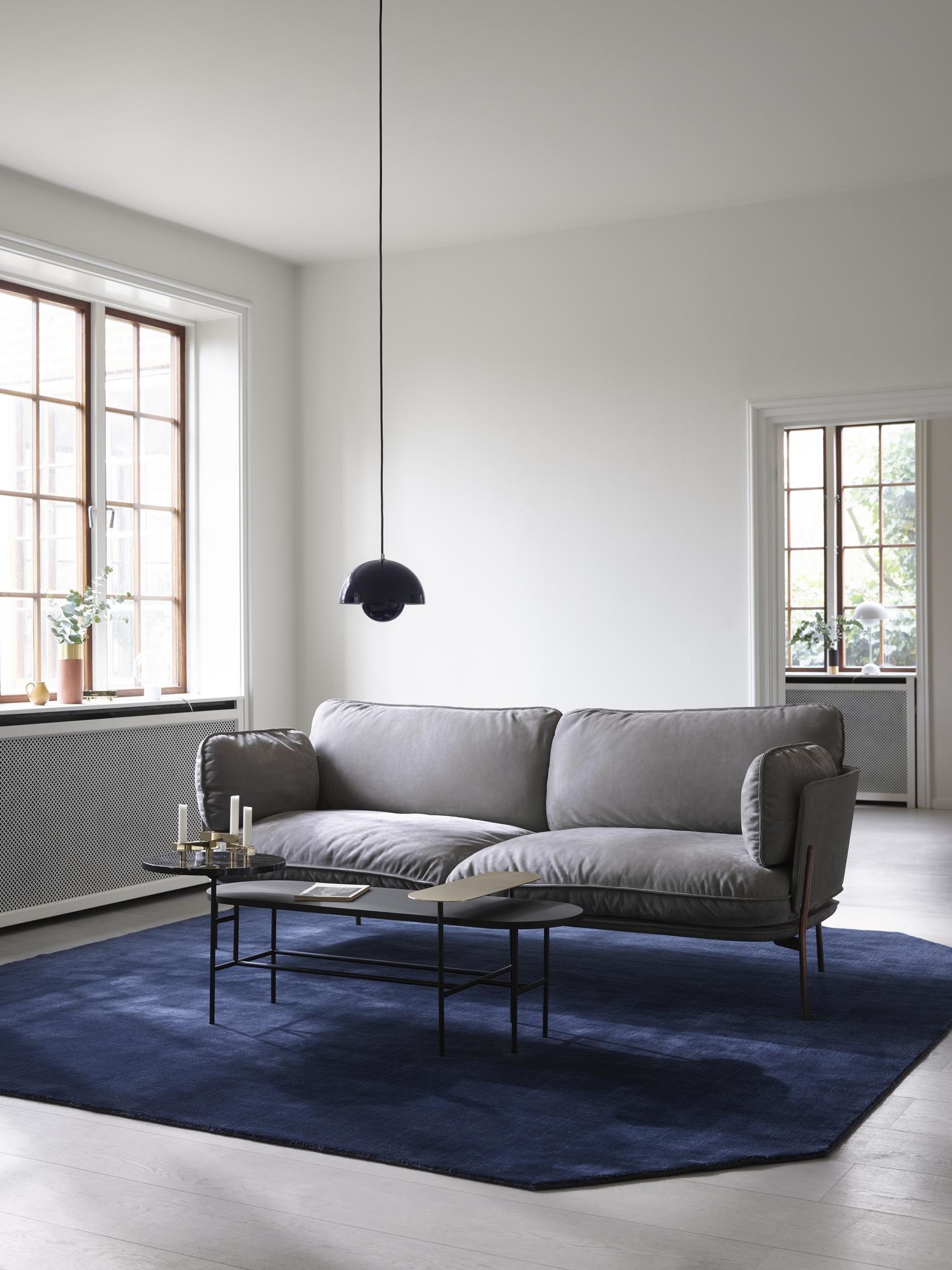 AndTradition Palette Table JH7 Couchtisch im Wohnzimmer mit grauer Couch und blauem Teppich.