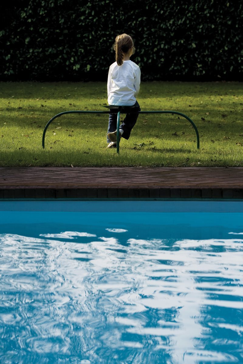 Mädchen sitzt auf Zanotta Allunaggio Stuhl im Garten am Pool, modernes Outdoor Möbel.