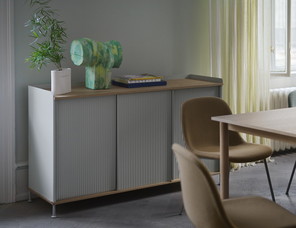 Graues Enfold Sideboard Low von Muuto mit geriffelten Schiebetüren und Deko im Wohnzimmer.