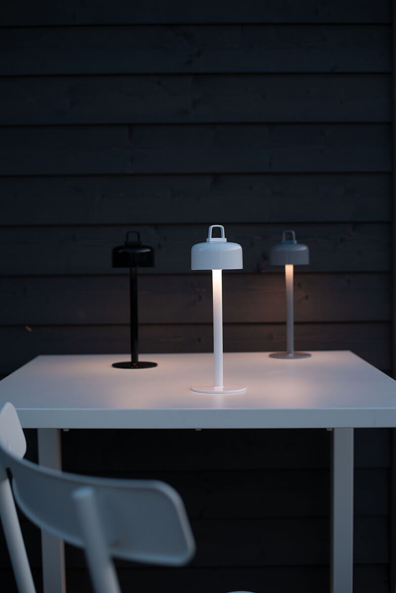 Drei Luciole Outdoor Leuchten von Emu in Schwarz, Weiß und Grau auf einem Tisch.