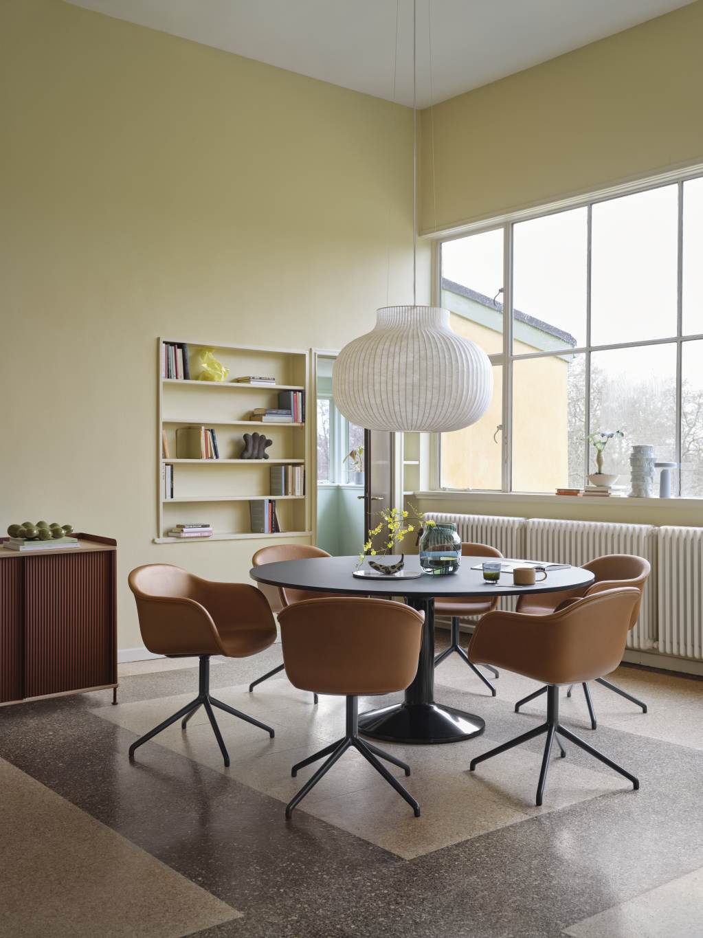 Esszimmer mit Muuto Sideboard, Esstisch, Stühlen und Pendelleuchte in hellem Raum.