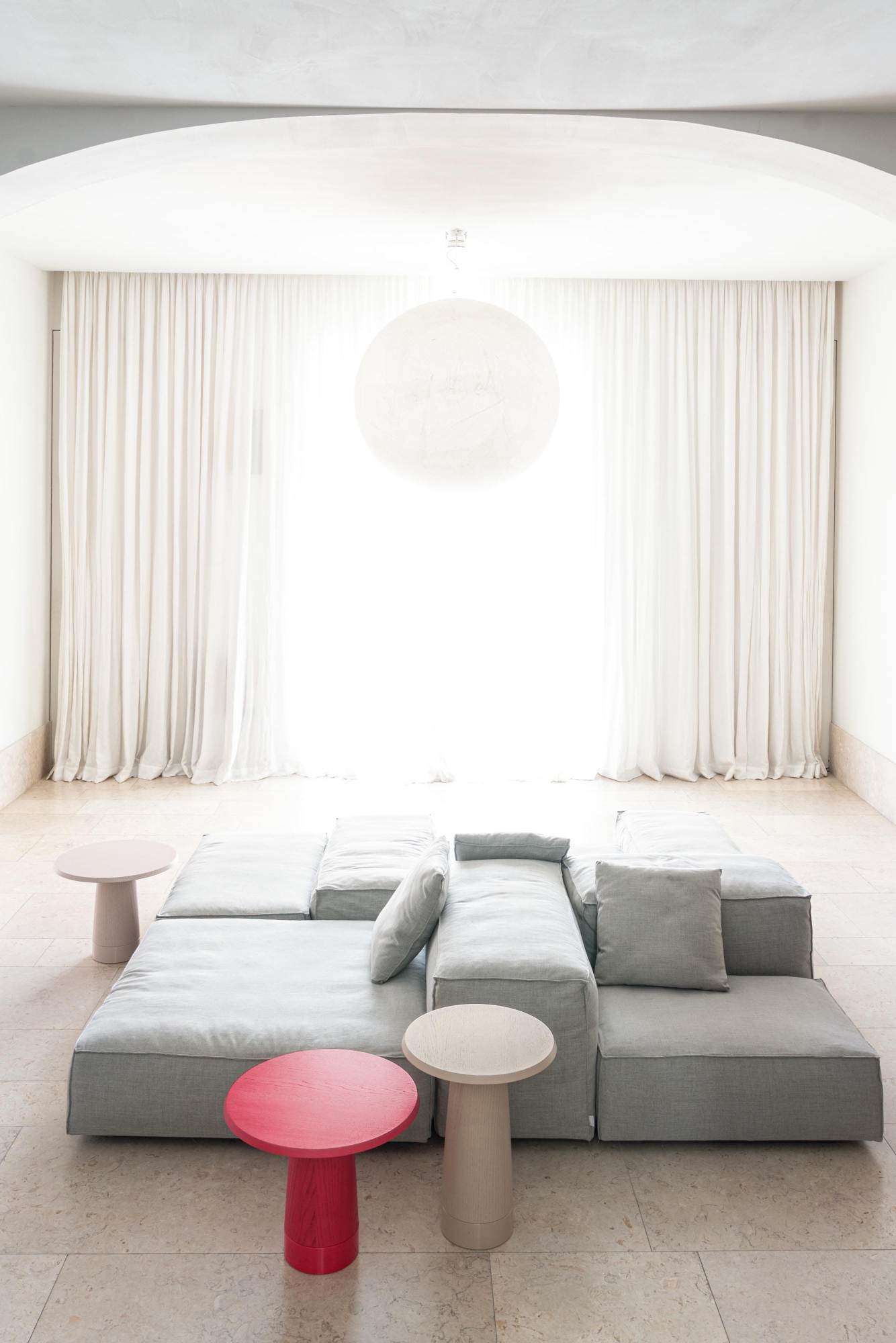 Wohnzimmer mit modularem Sofa und drei Schönbuch Amanita Beistelltischen in Rot, Beige und Rosa.