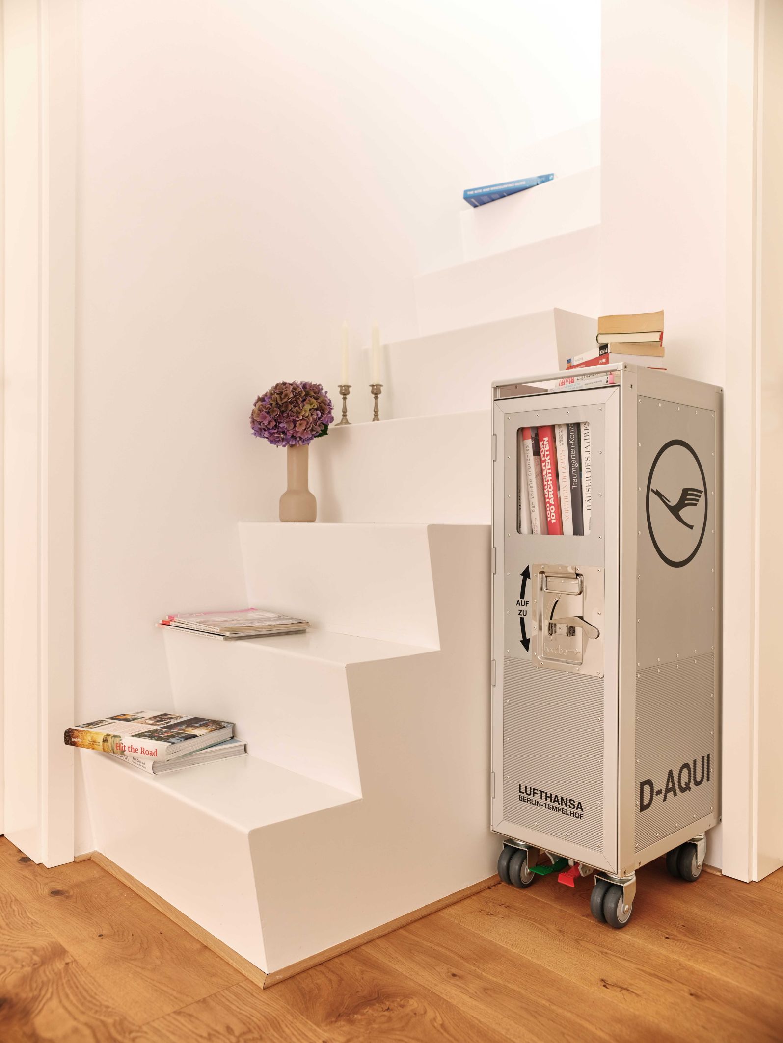 Lufthansa Bordbar Flugzeugtrolley als Bücherregal neben einer Treppe. Möbel aus dem Flugzeugbereich.