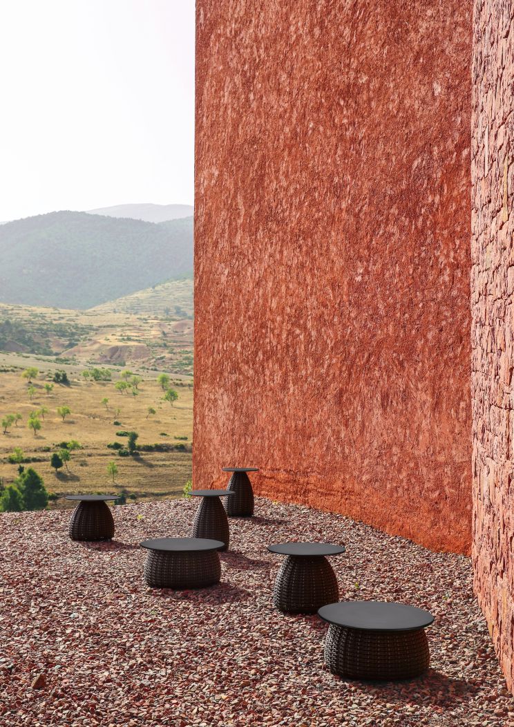 Dedon Porcini Beistelltische Ø61cm im Außenbereich mit rotem Kies und Berglandschaft im Hintergrund.