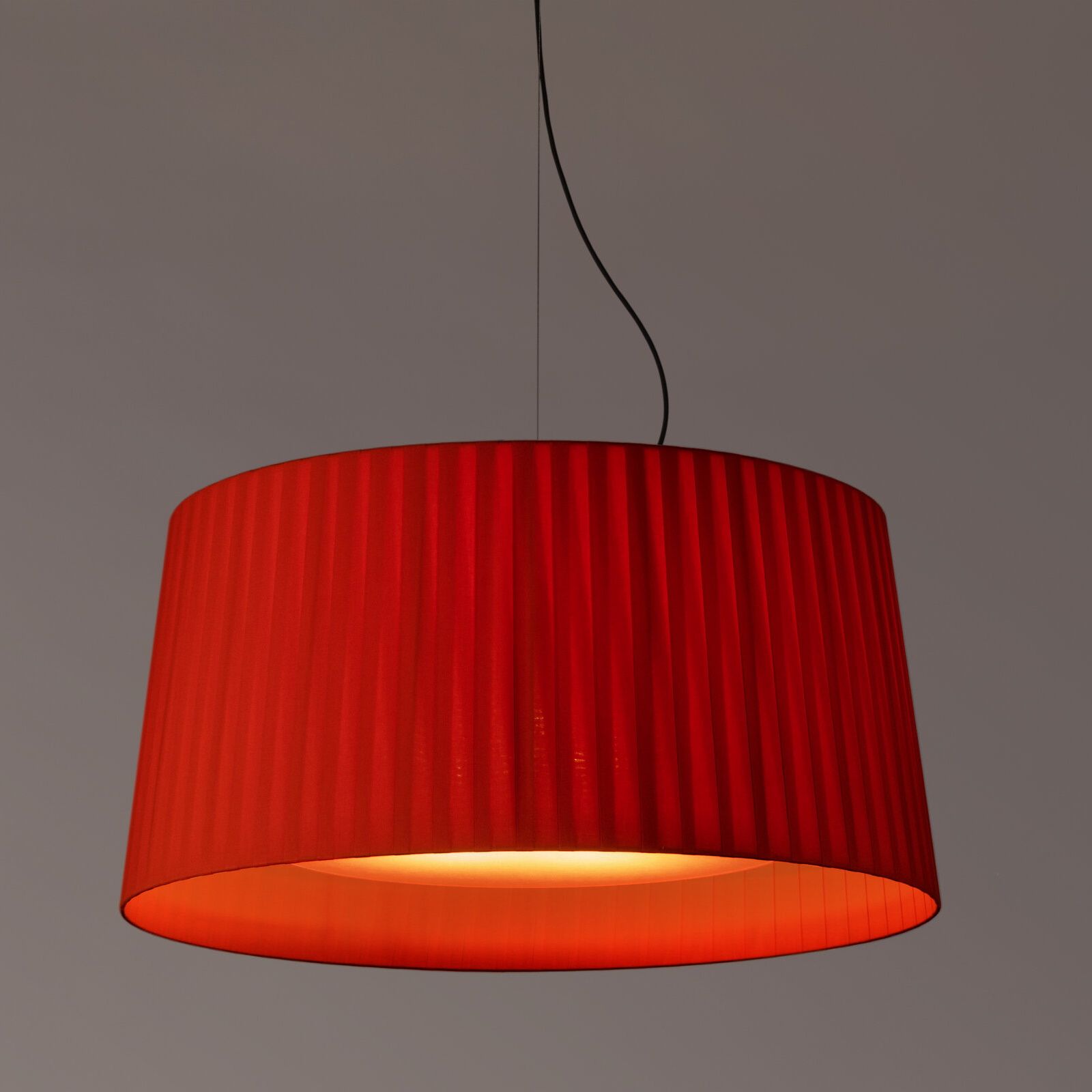 Rote GT7 Pendelleuchte von Santa & Cole mit plissiertem Lampenschirm und warmem Licht.