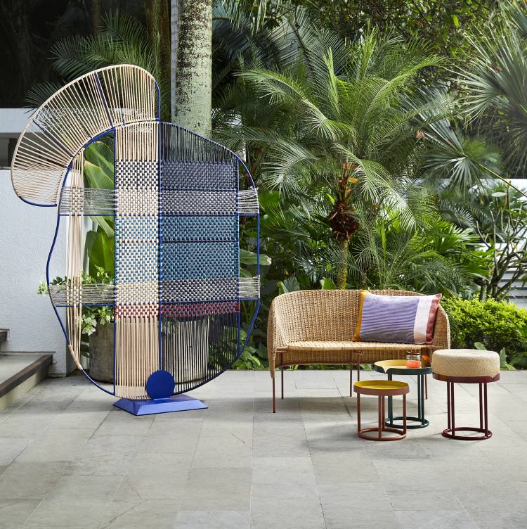 Ames Caribe Natural 2-Sitzer Outdoor Bank mit passenden Hockern und dekorativem Raumteiler im Garten.