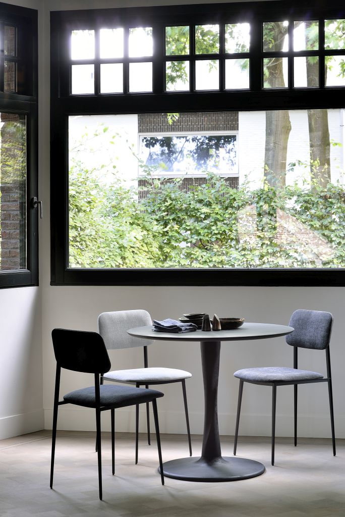 Torsion Eiche Tisch von Ethnicraft mit schwarzem Untergestell und drei Stühlen in modernem Esszimmer.