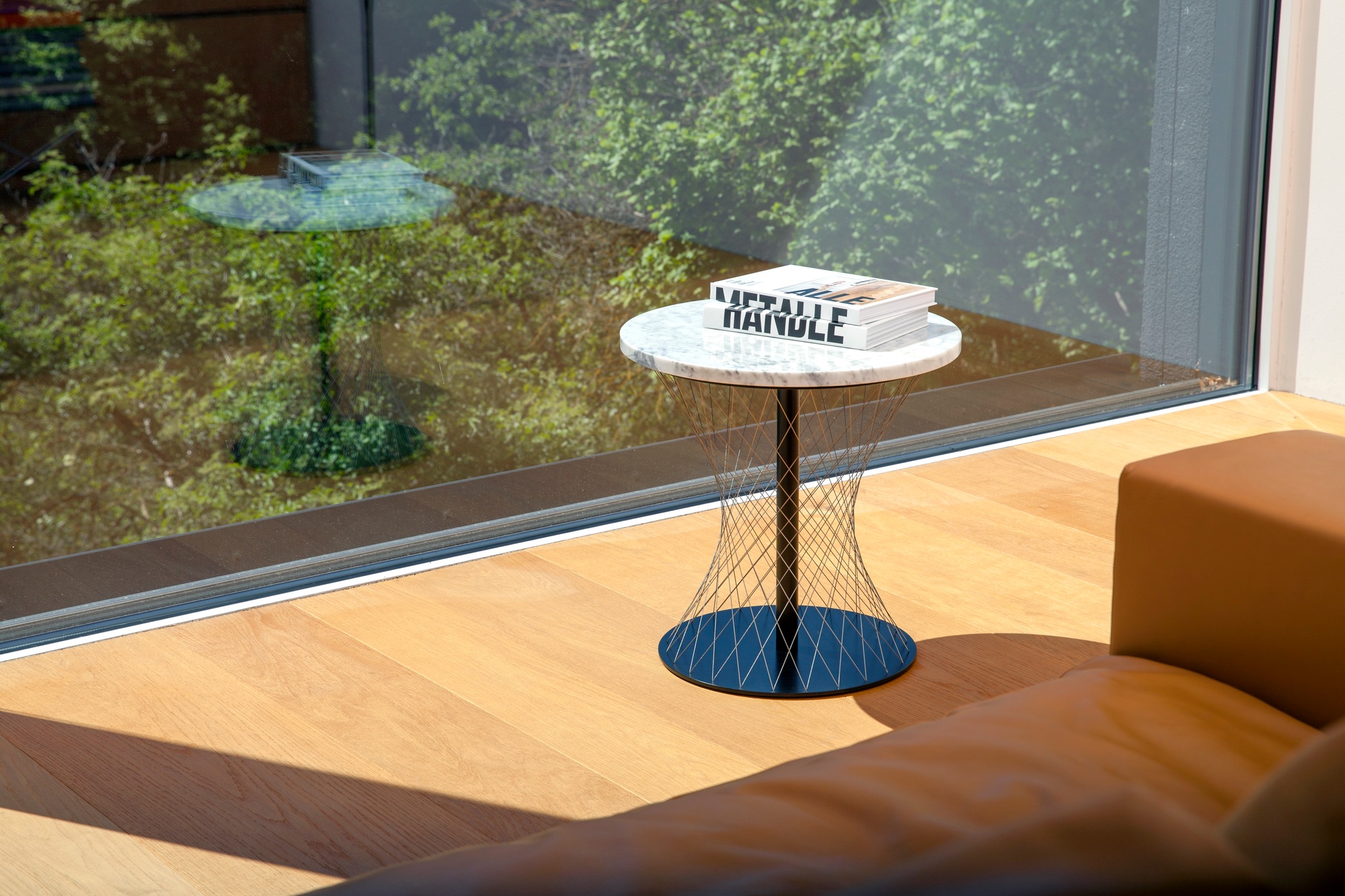 Weißer Network Beistelltisch Favius mit Marmorplatte und filigranem Drahtgestell neben einem Fenster.