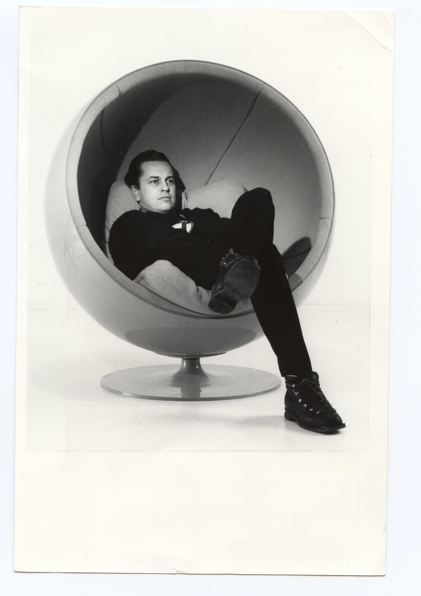 Mann entspannt im grauen Ball Chair Sessel, ein Designklassiker von Eero Aarnio Originals.
