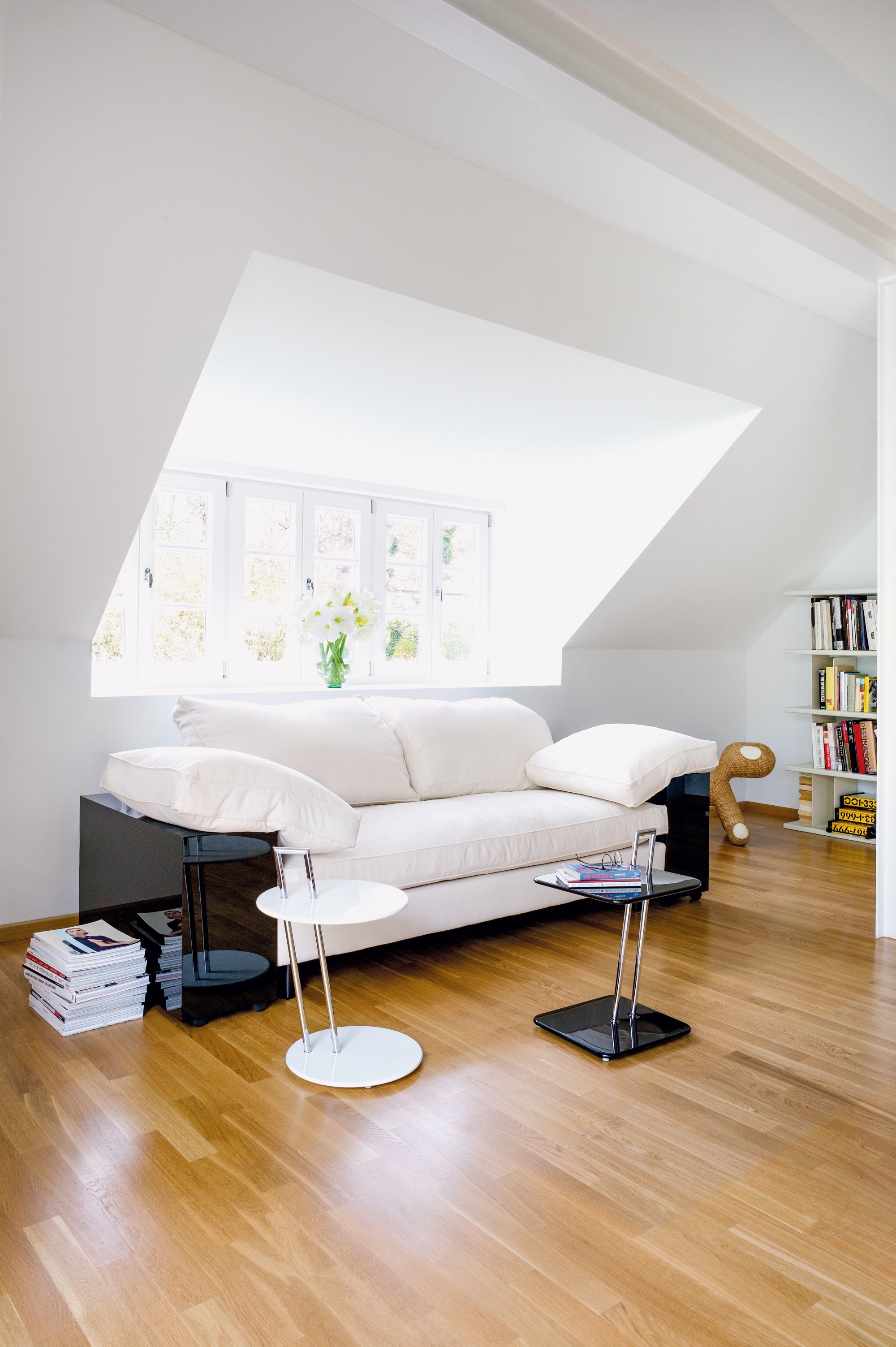 Helles Wohnzimmer mit Classicon Lota Sofa, Beistelltischen und Bücherregal unter einer Dachschräge.