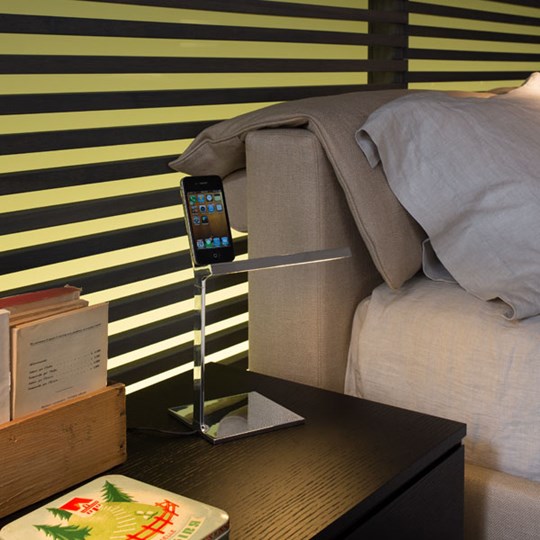 D´E-light Tischleuchte von Flos aus Chrom auf Nachttisch mit Smartphone. Design Lampe für Schlafzimmer.
