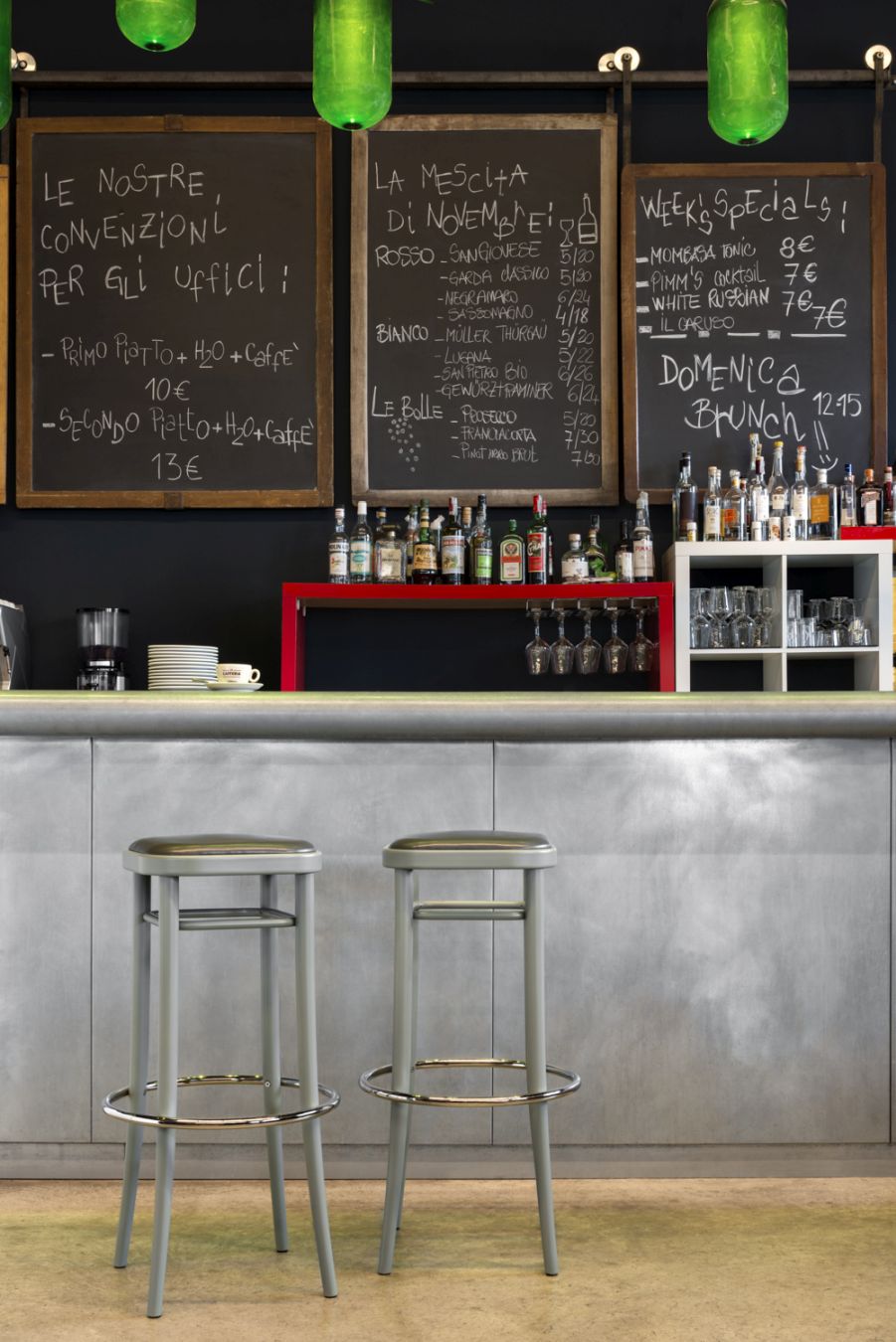 Zwei graue Vienna 144 Barhocker mit Schichtholzsitz vor einer Bar mit Getränken.