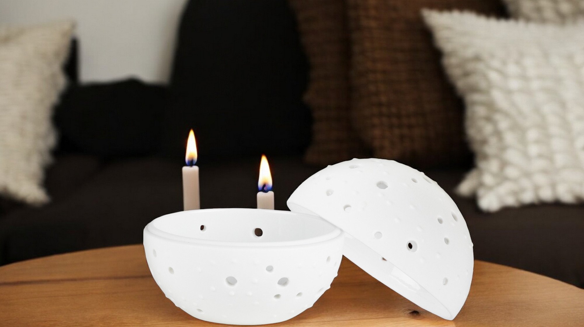 Weiße Living Wunderkugel mit Punktmuster, offen präsentiert, neben brennenden Kerzen als stimmungsvolle Dekoration.