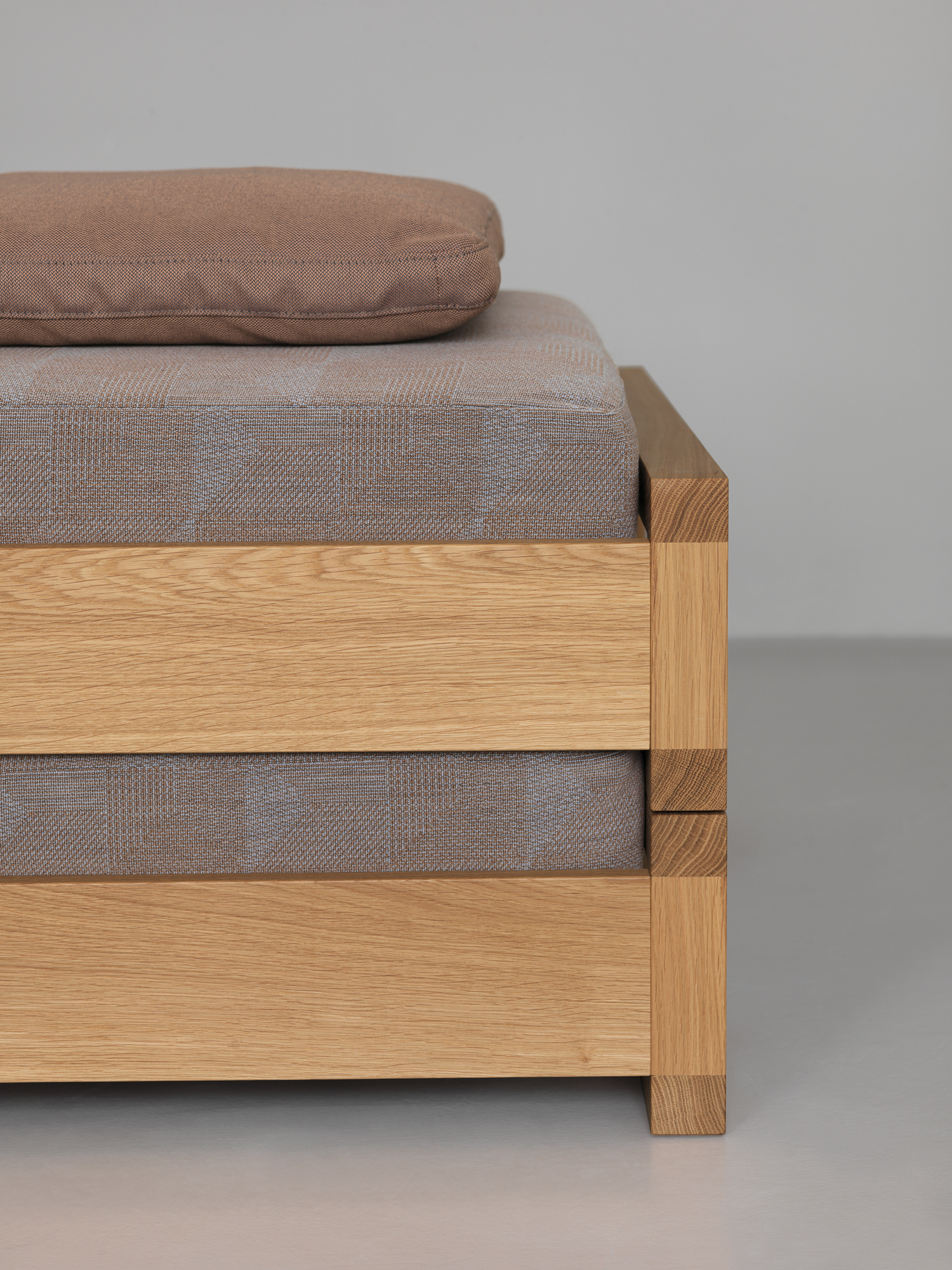 Detailaufnahme vom Guest 90 Holzbett Eiche mit braunem Kissen und Stoffbezug. Massivholzbett für Schlafzimmer.