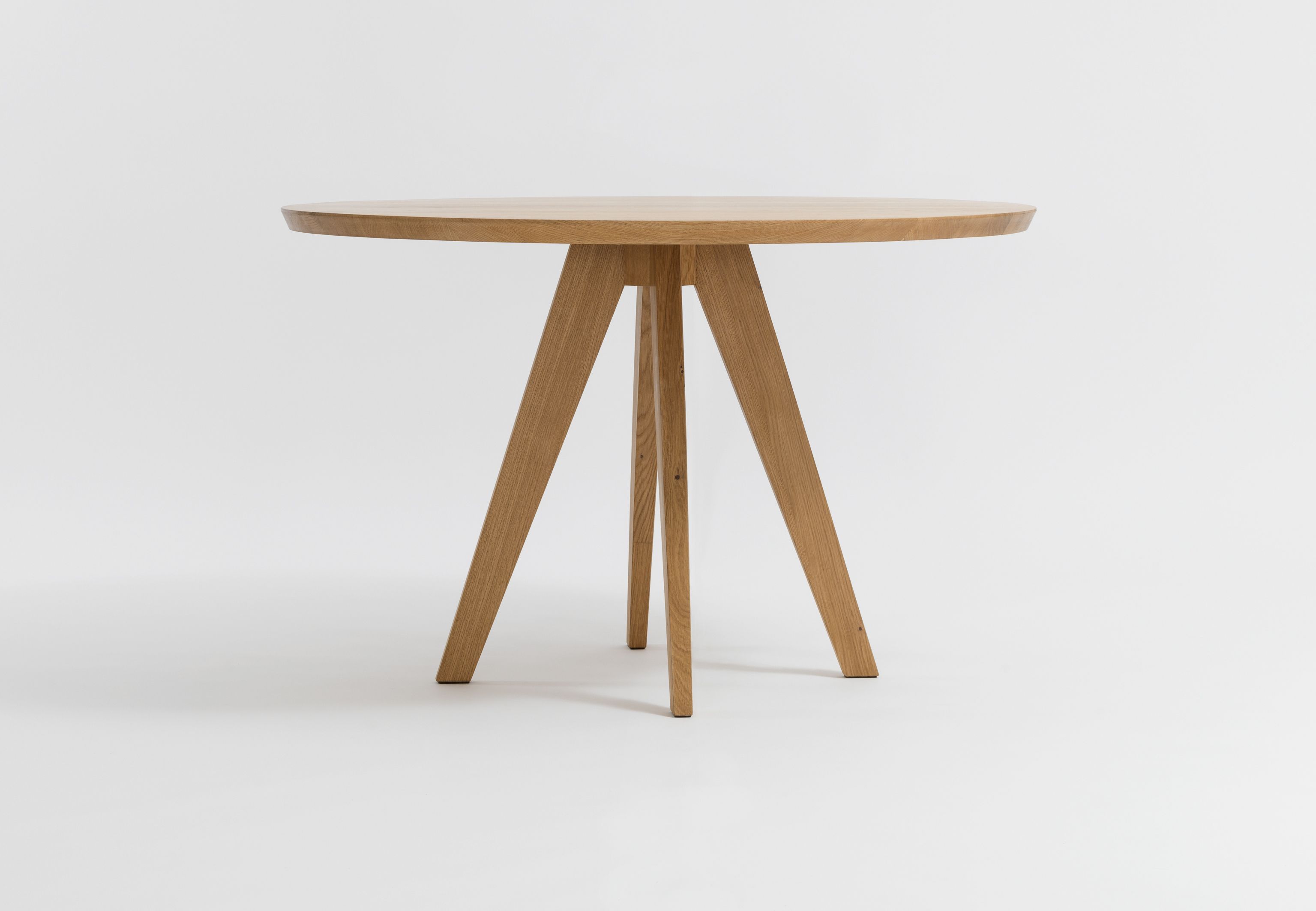 CENA Tisch: Runder Esstisch aus hellem Holz mit drei Beinen vor weißem Hintergrund.