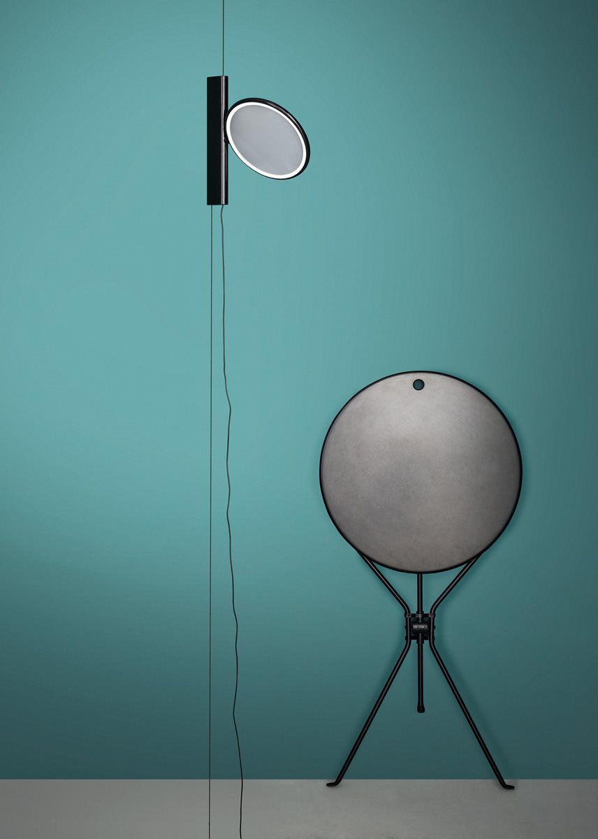 Cumano Klapptisch von Zanotta, zusammengeklappt an Wand gelehnt, mit Wandlampe im minimalistischen Design.