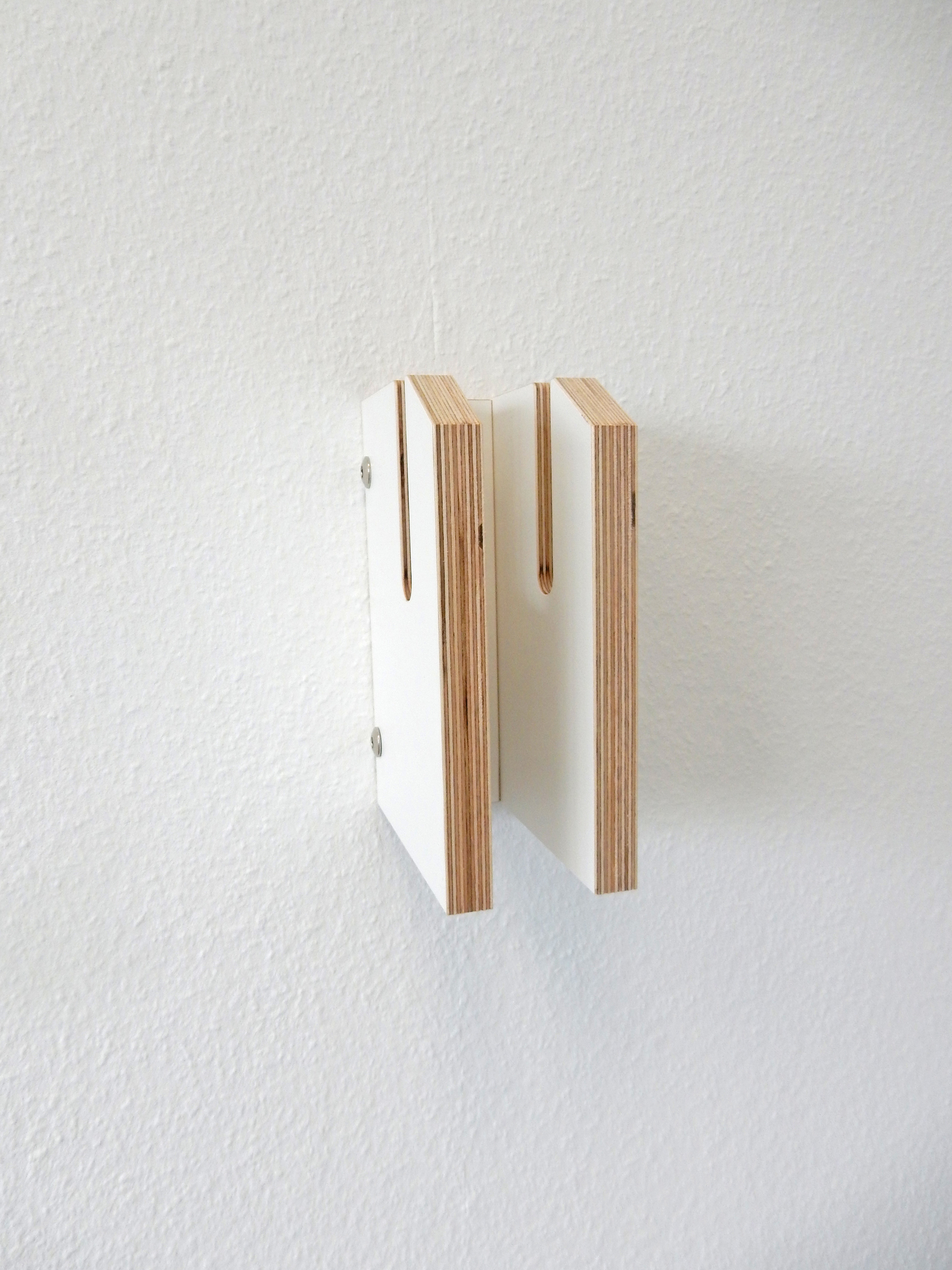 Zwei weiße Tojo Lesestoff Bücherregal-Elemente aus Holz an einer weißen Wand befestigt.