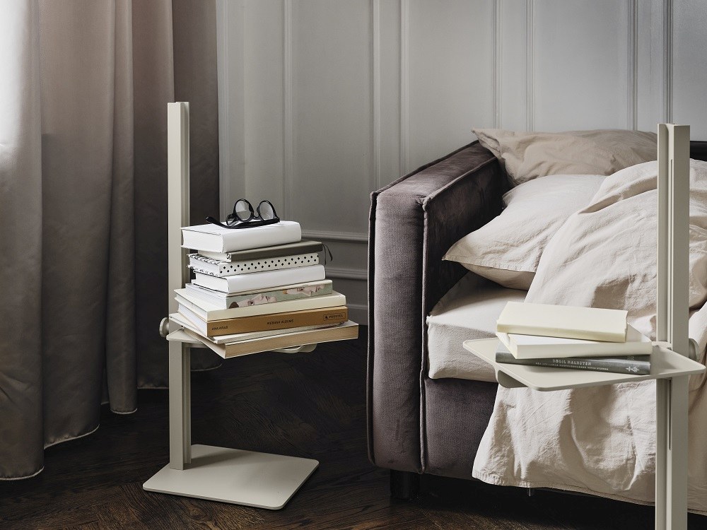 Beige Museum Sidetable Beistelltisch von String Furniture, höhenverstellbar, mit Büchern dekoriert neben einem Sofa.