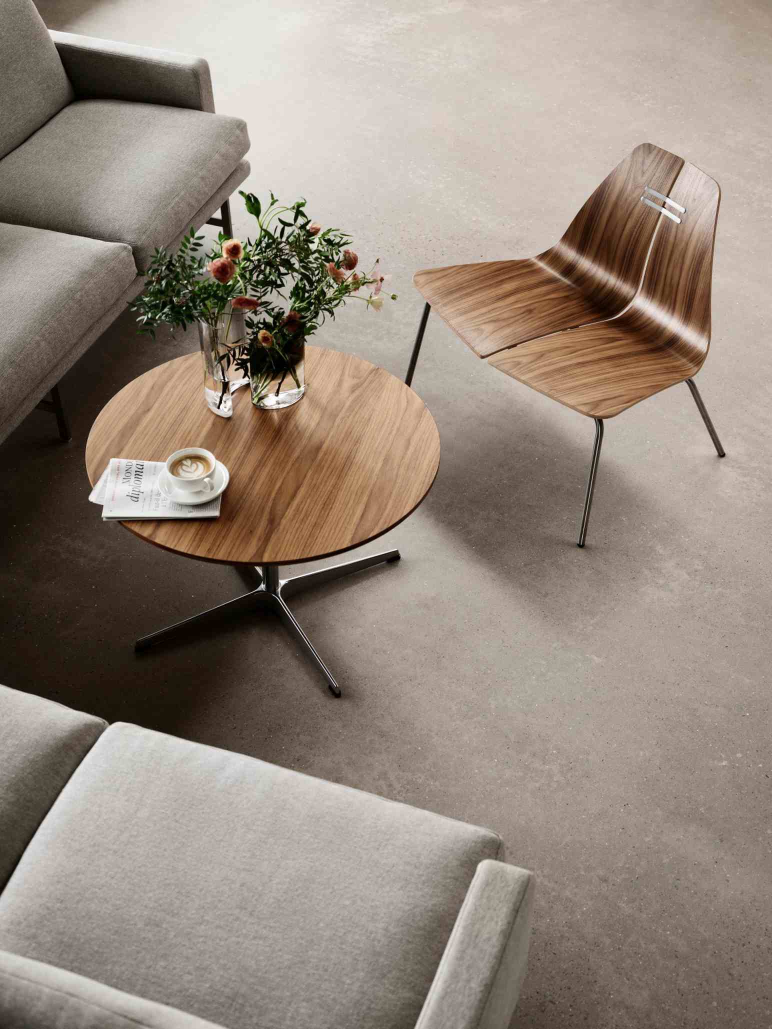 PK23 Loungesessel von Fritz Hansen aus Holz mit Stahlbeinen neben Couch und Tisch.