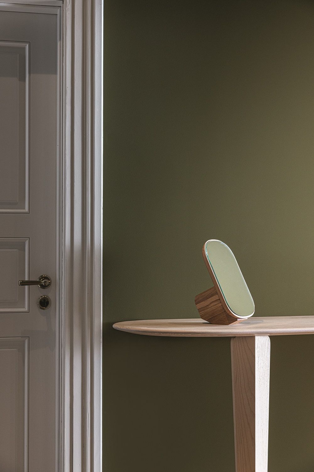 Kuyu Console Tisch mit asymmetrischer Form und Spiegel auf einer hellen Holzoberfläche.