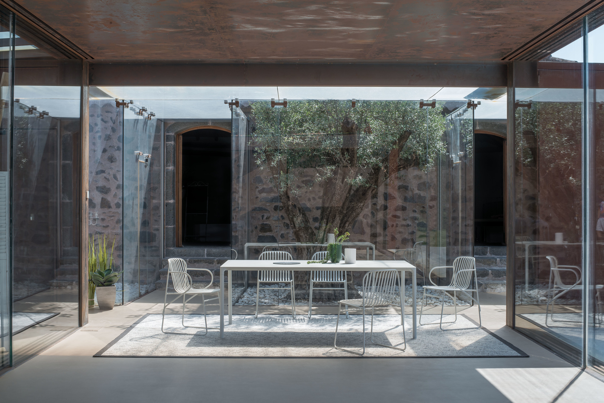 Heller Riviera Stuhl von Emu, ein moderner Gartenstuhl aus Metall, Teil einer stilvollen Essgruppe.