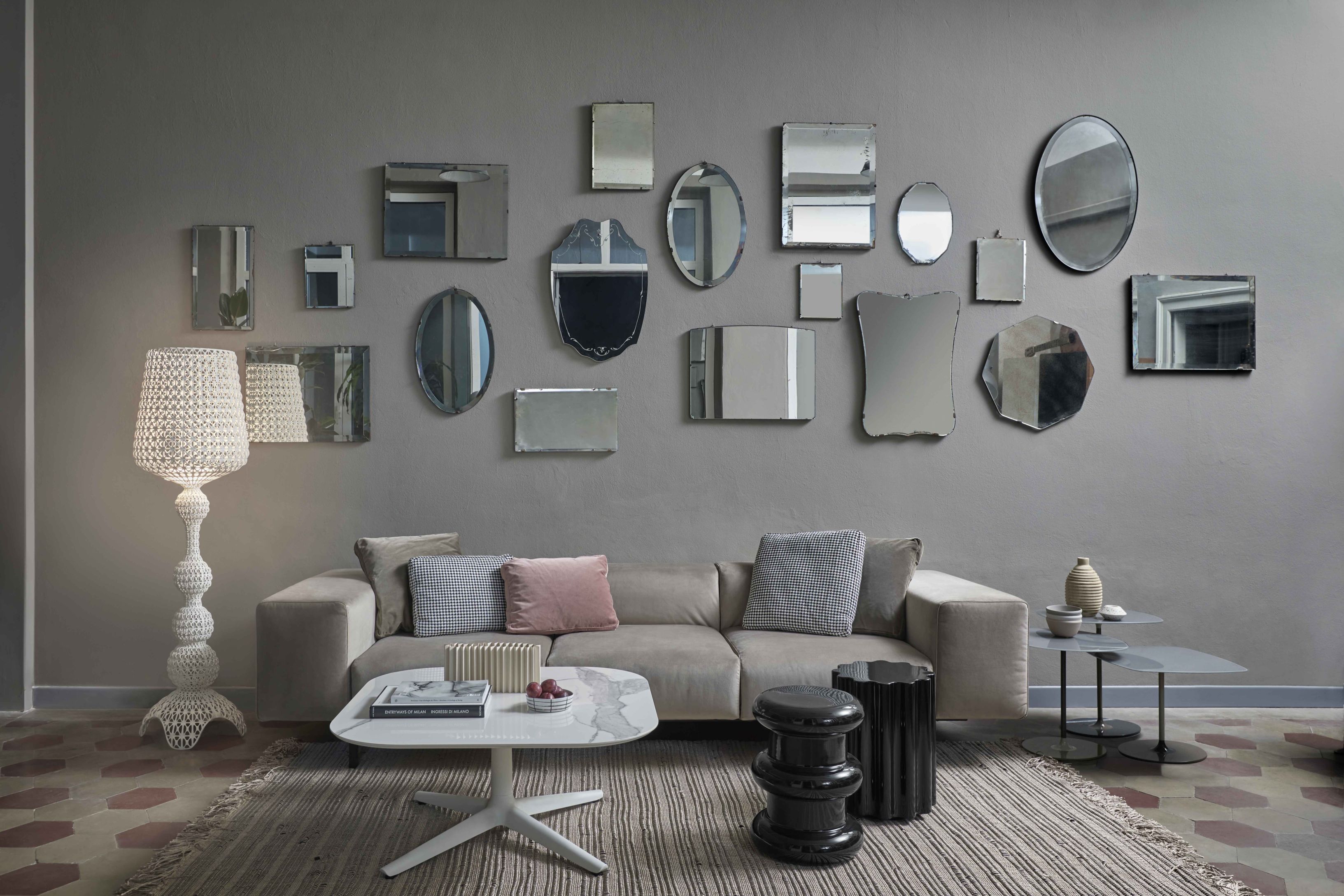 Wohnzimmer mit Kabuki Stehleuchte von Kartell, Sofa, Couchtisch und Spiegeln an der Wand.