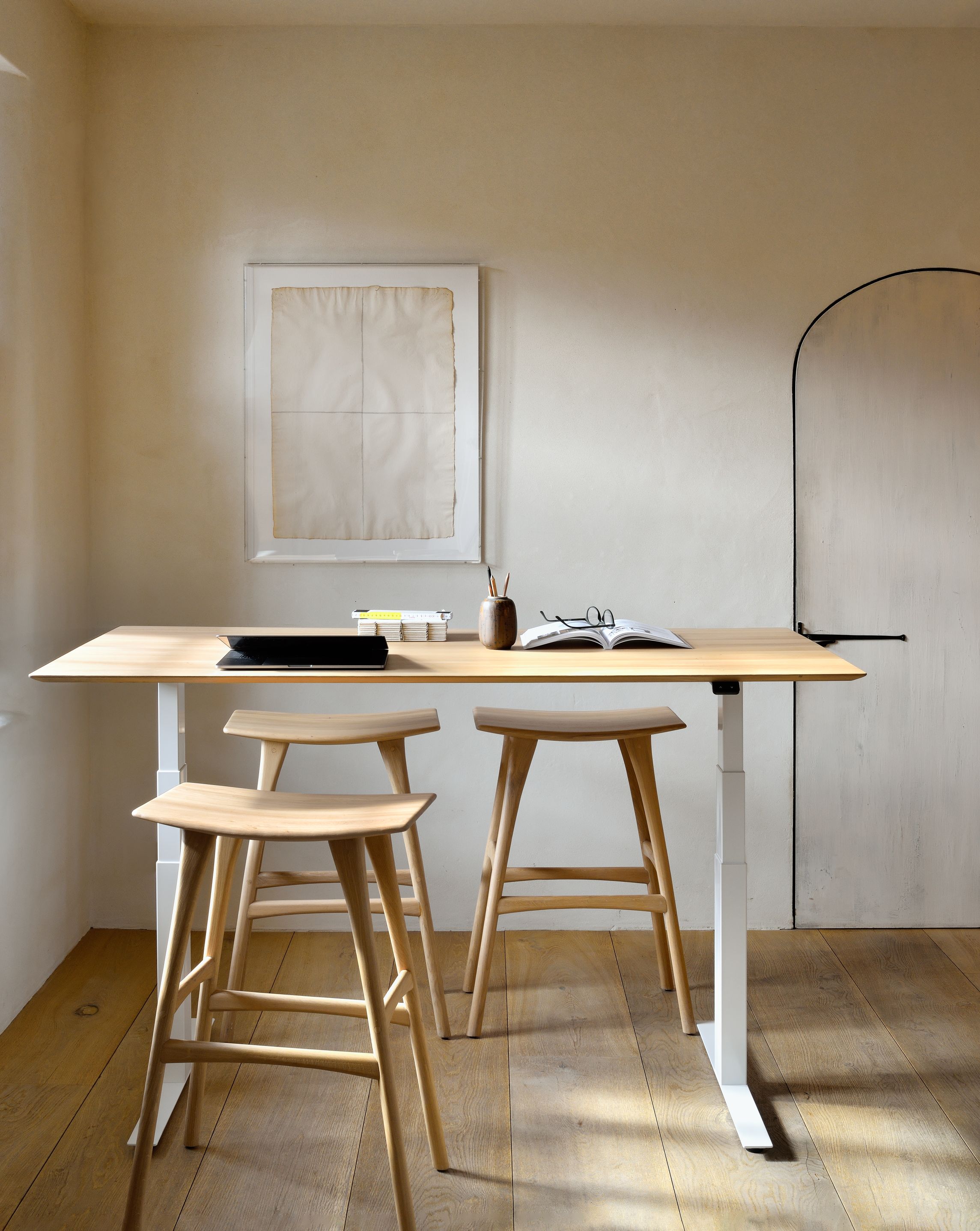 Zwei Osso Barhocker aus Eiche von Ethnicraft an einem höhenverstellbaren Schreibtisch in einem hellen Raum.