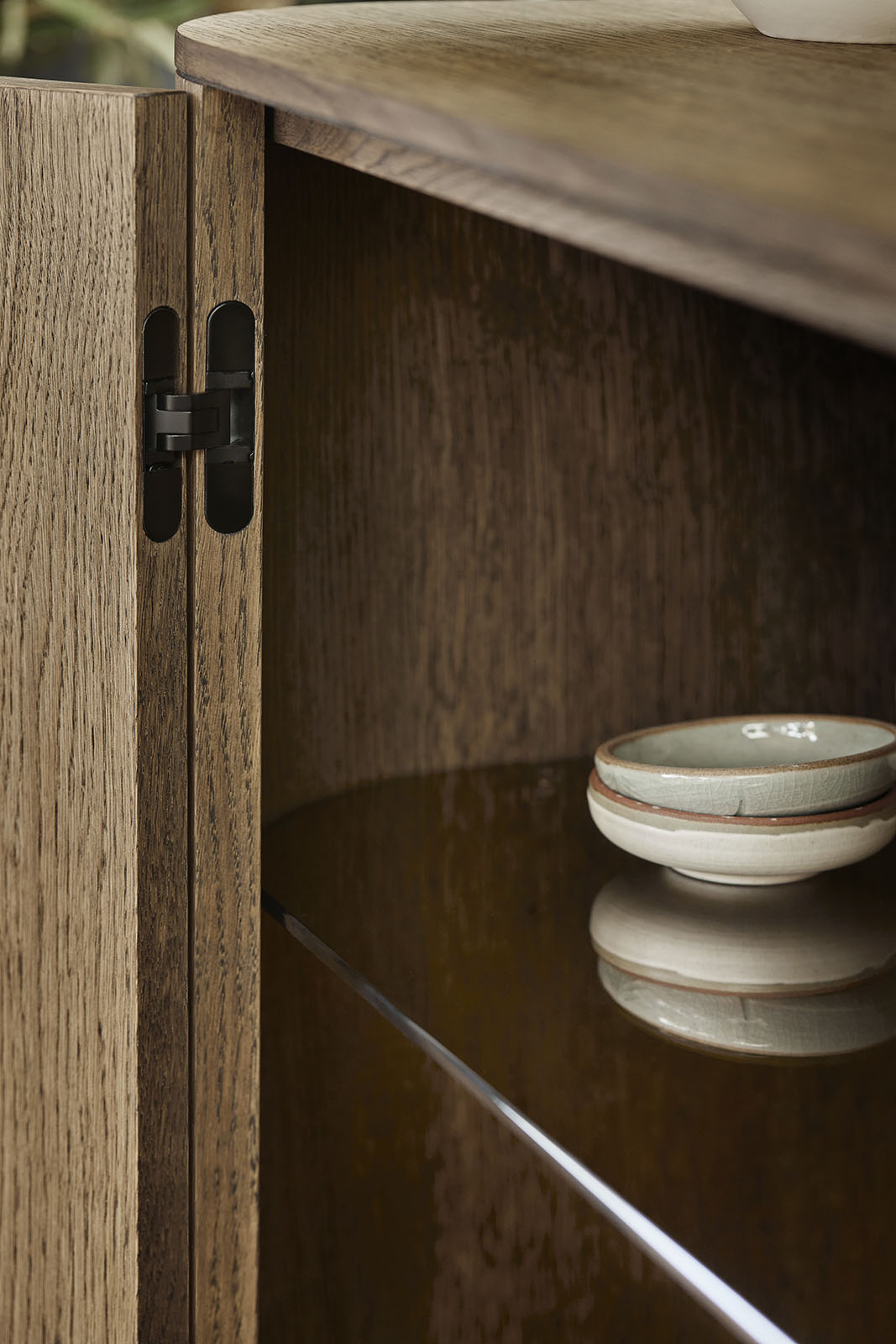 Detailaufnahme: Helles Eichen-Sideboard mit Türscharnier und Glasboden, moderne Wohnzimmermöbel.