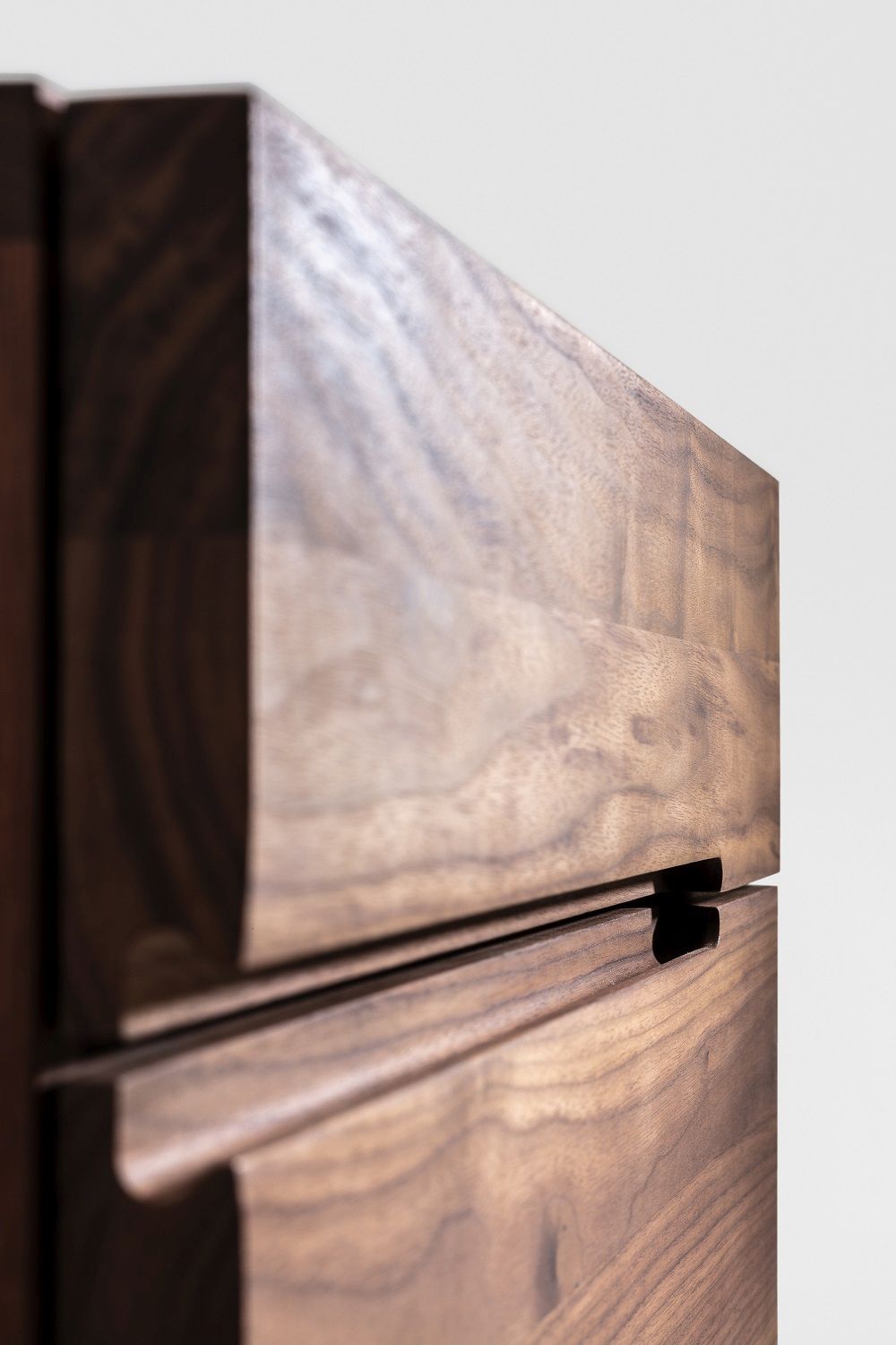 Detailaufnahme des Nightstand 64 Nachttischs aus dunklem Walnussholz mit Schubladen und Griffmulden.