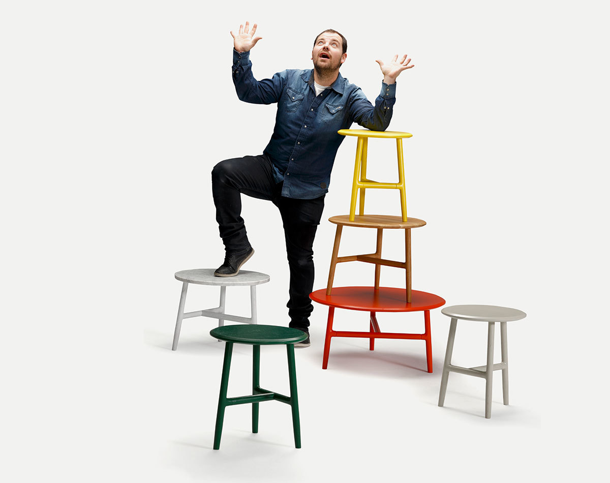 Mann posiert mit farbenfrohen Nudo Beistelltischen von Sancal, runde Tischplatten, modernes Design.