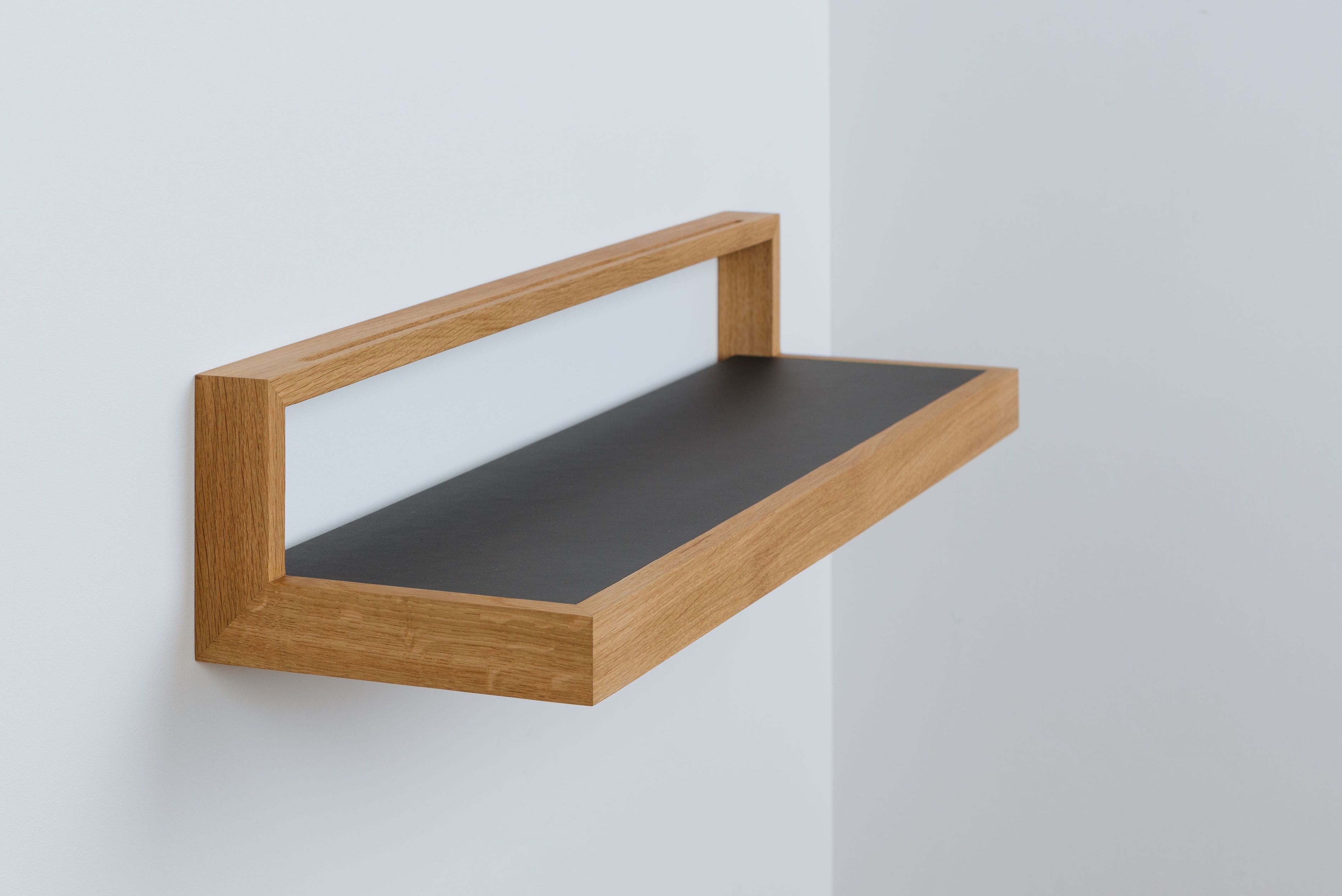 Anthrazitfarbenes Ablageboard "buck2" mit hellem Holzrahmen an weißer Wand. Wandregal für Bücher und Deko.