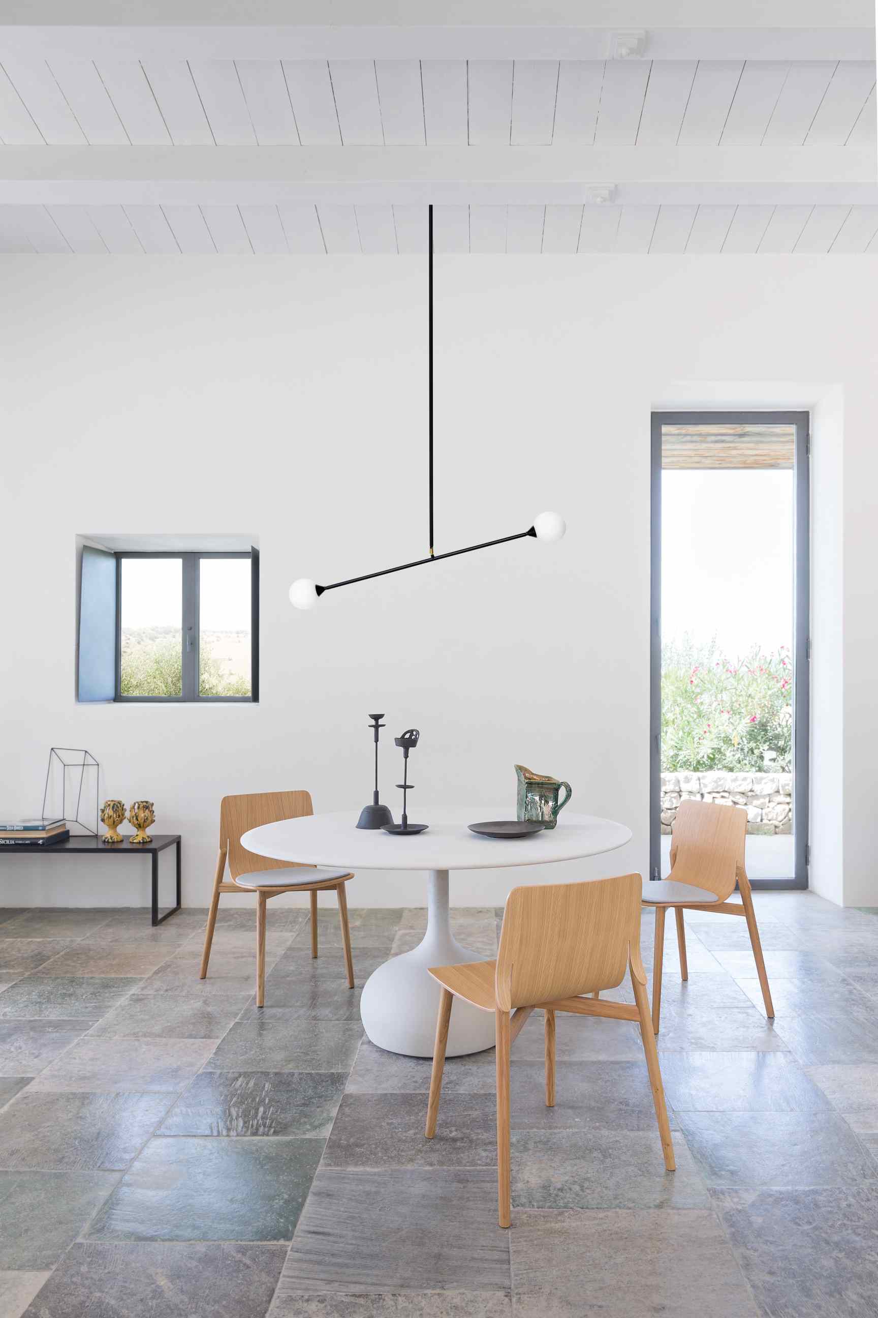 Saen Esstisch mit runder, weißer Tischplatte und Holzstühlen in hellem Raum. Moderner Esstisch für Esszimmer.