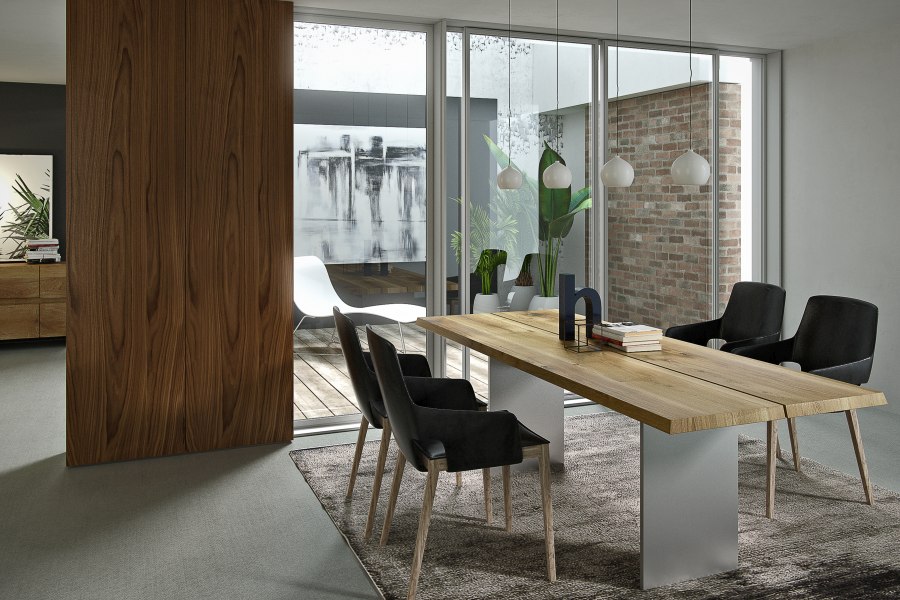 Moderner Natt Esstisch Trebord aus Holz mit schwarzen Stühlen in einem hellen Esszimmer.