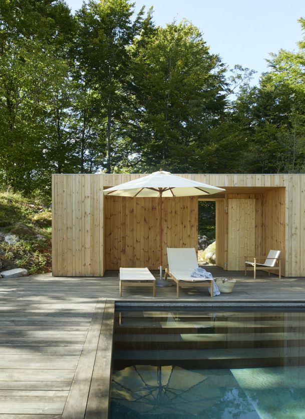 Pelagus Sonnenliege von Skagerak by Fritz Hansen am Pool auf Holzterrasse mit Sonnenschirm.