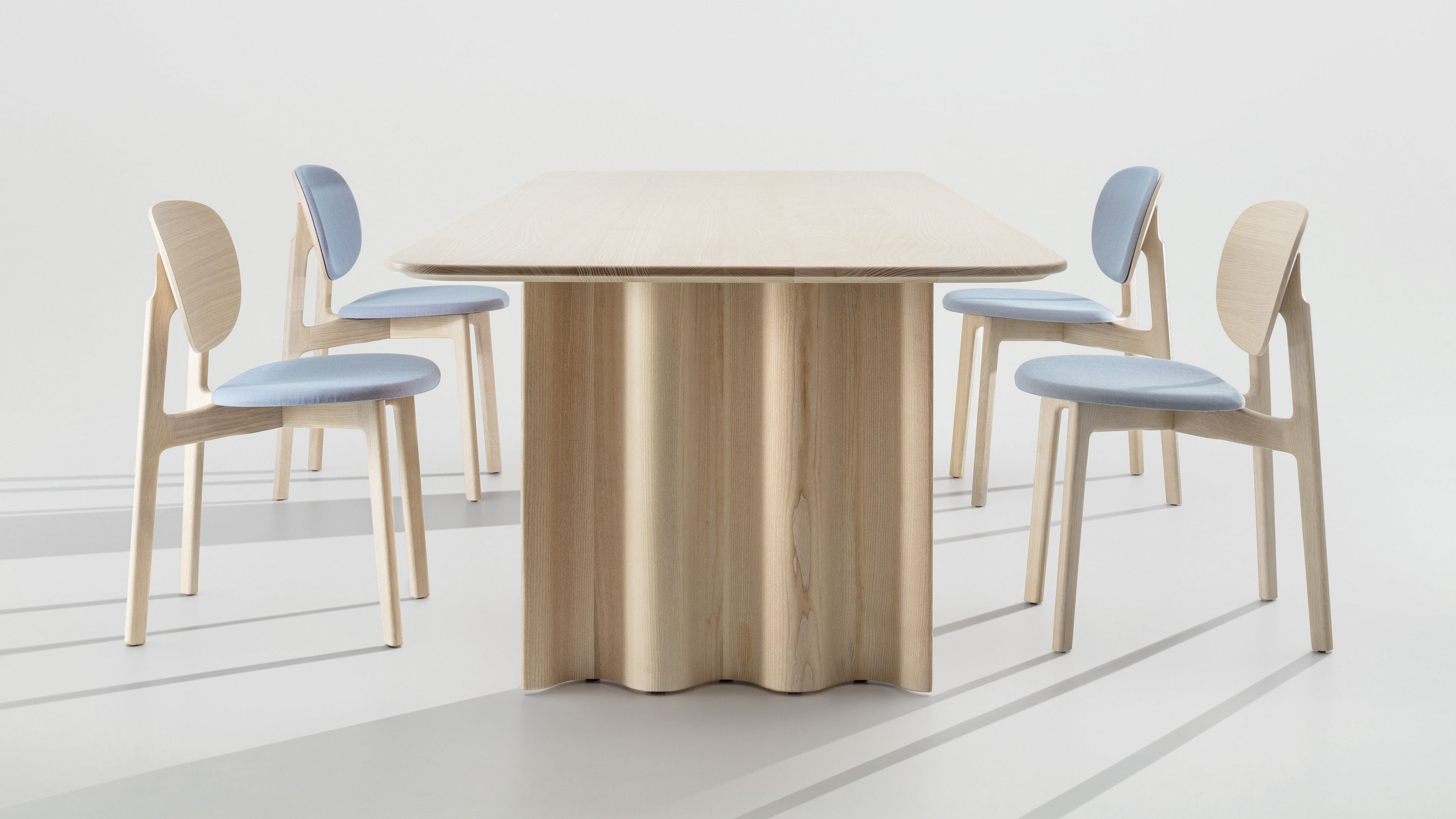 Curtain Tisch: Rechteckiger Esstisch aus hellem Holz mit passenden Stühlen und blauen Sitzflächen.