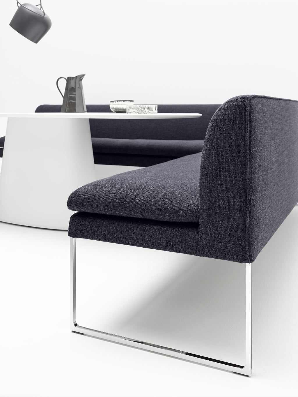 Nahaufnahme der Mell Polsterbank von Cor, eine moderne Sitzbank mit grauem Stoffbezug und Chromgestell.