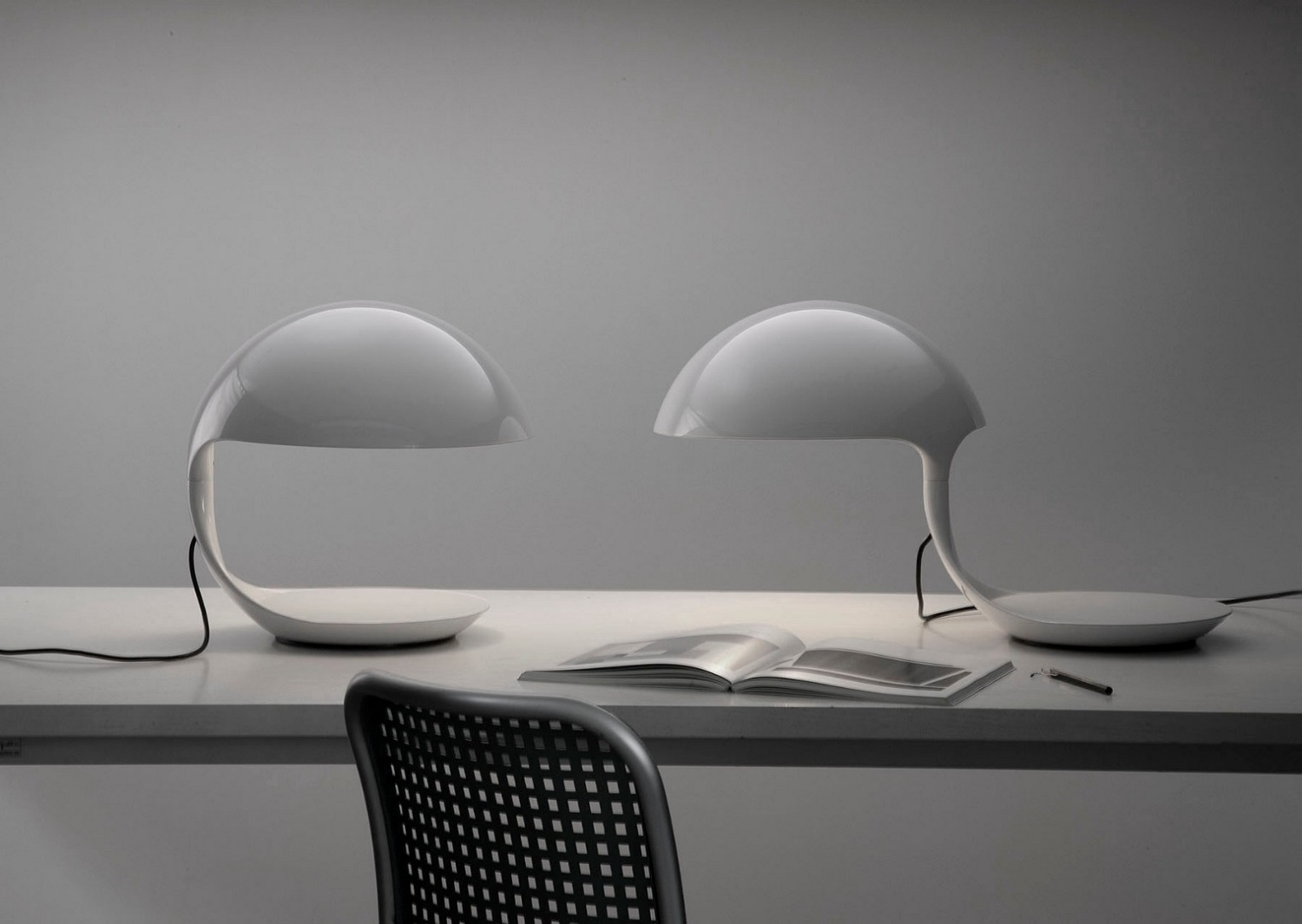 Zwei weiße Cobra Tischleuchten von Martinelli Luce auf einem Schreibtisch mit Buch.