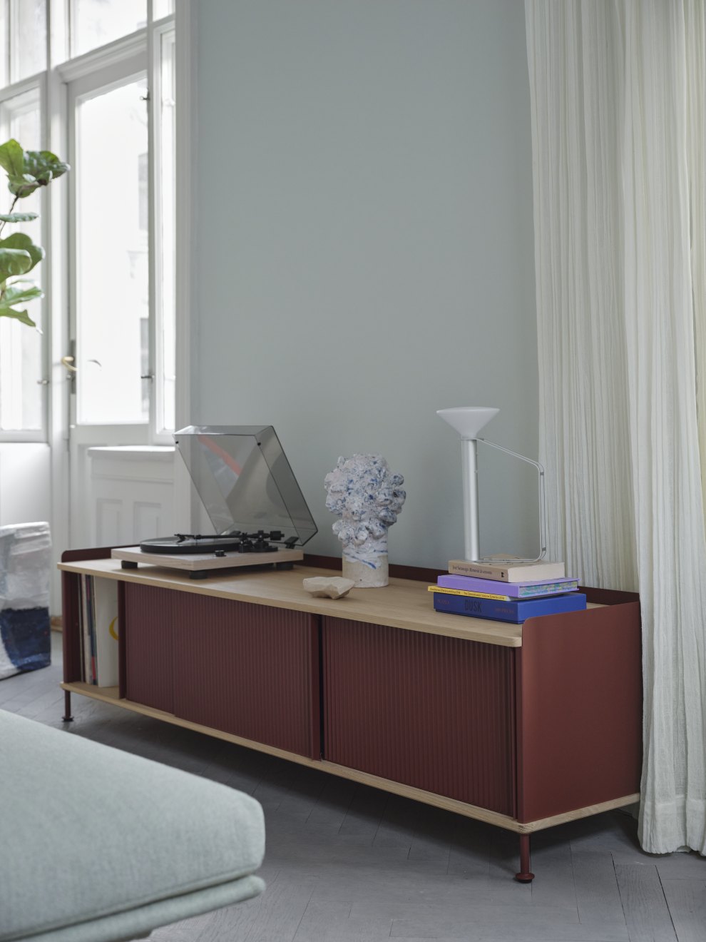 Enfold Sideboard Low von Muuto in Rotbraun mit Schiebetüren und Plattenspieler im Wohnzimmer.
