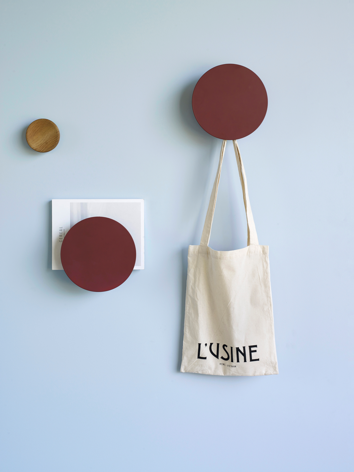 Wanddekoration mit rotem Metall Knopf Magazinhalter, Zeitschriften und Stoffbeutel an hellblauer Wand.