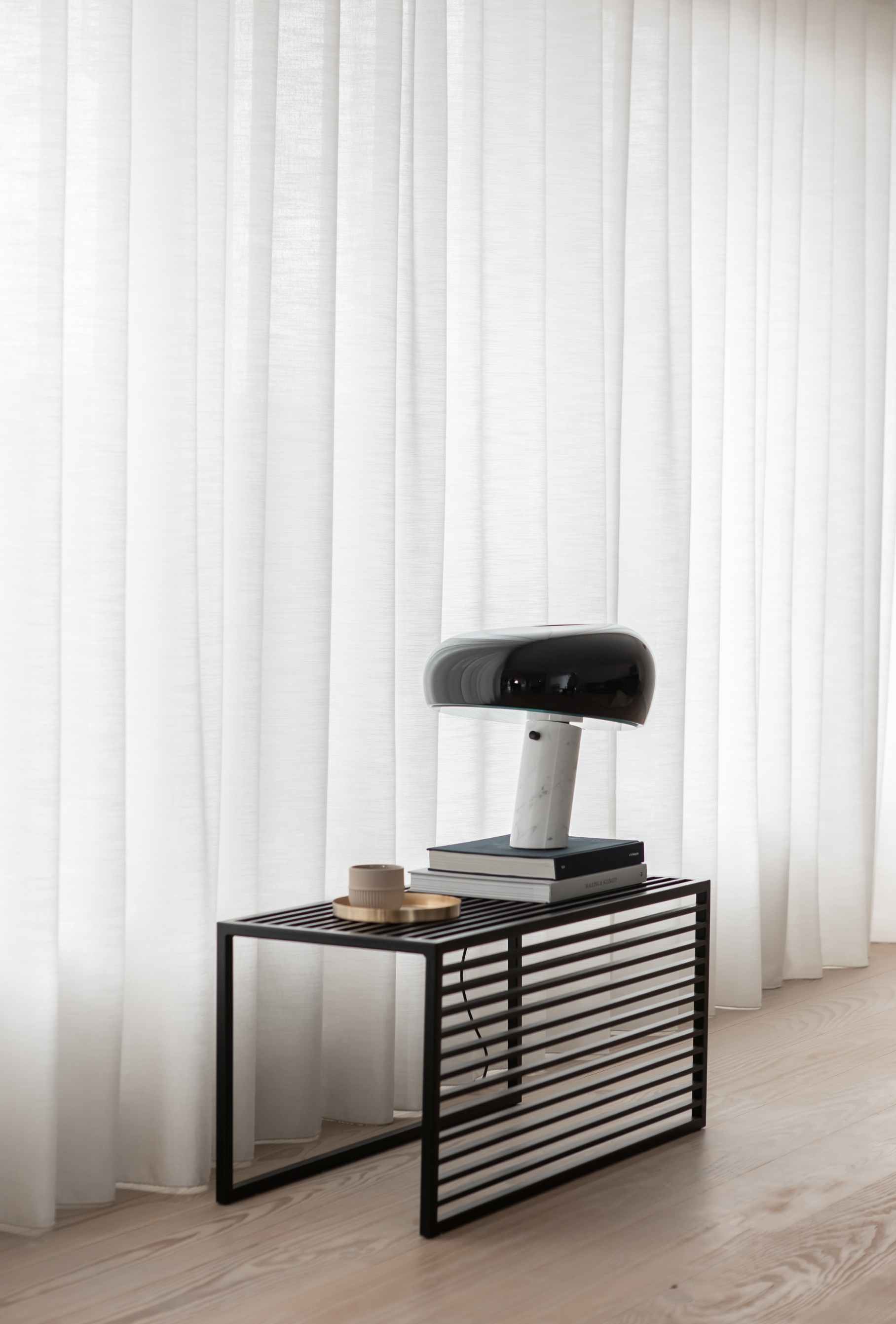 Element Bench Bank novoform: Schwarze Bank mit Lamellen, darauf Lampe, Bücher und Tasse.